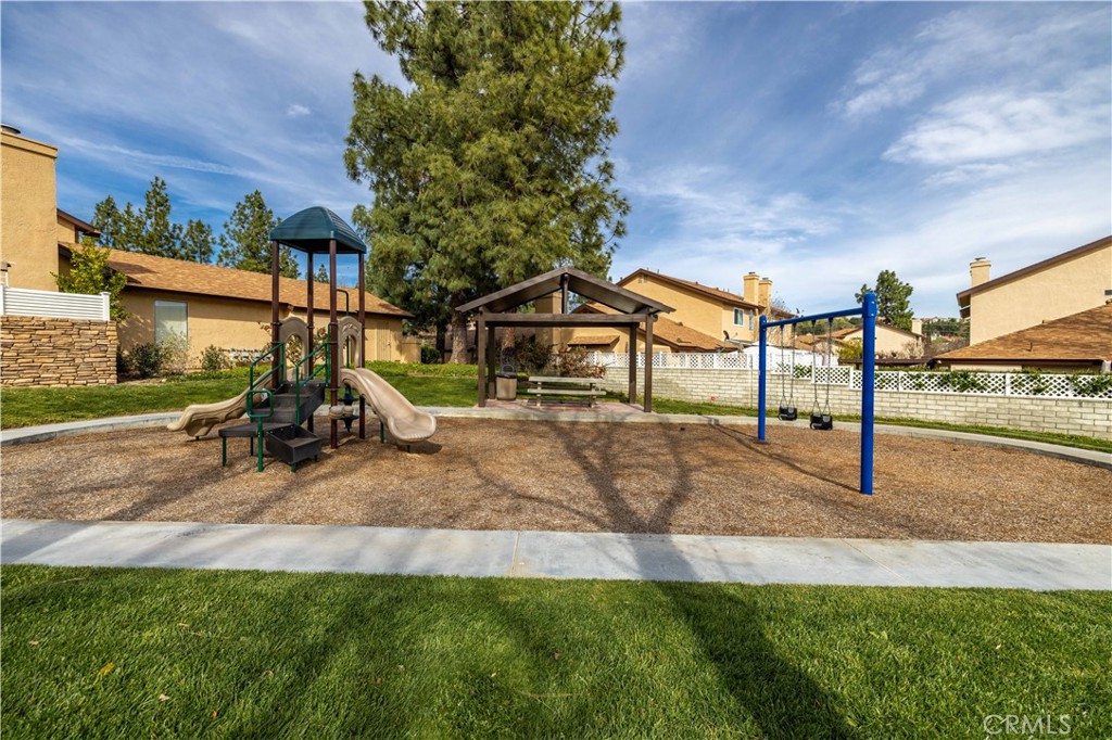 Neighborhood playground with slides, swings, and a covered bench shelter.
