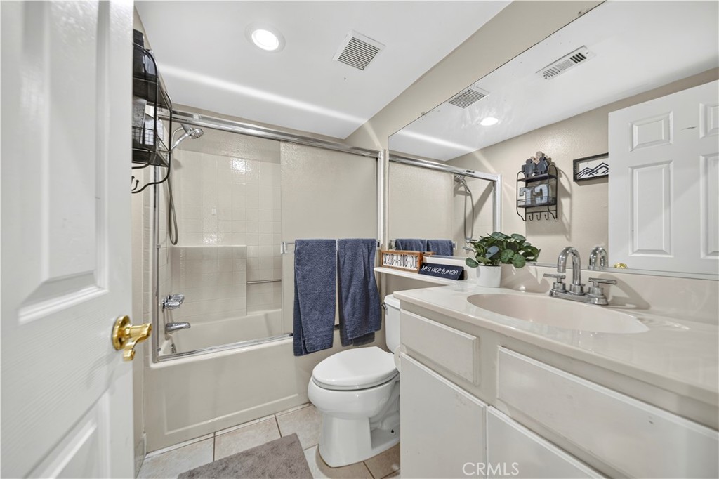 Bathroom with a glass-enclosed tub and shower, white vanity, and toilet.