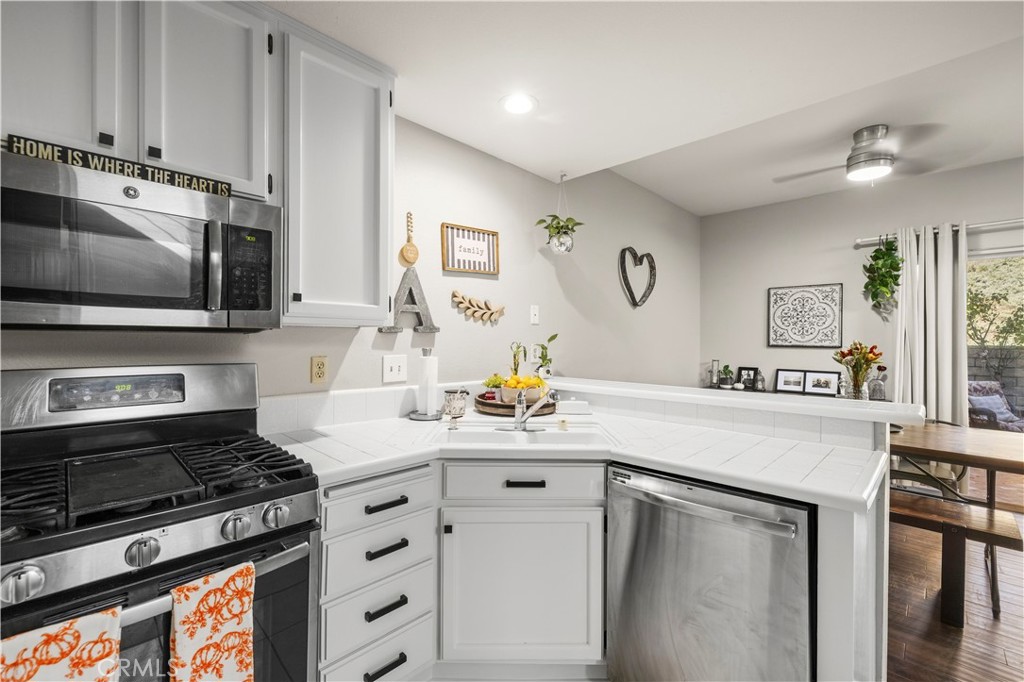 White kitchen with stainless steel appliances, a gas range, and a dining area beyond the counter.