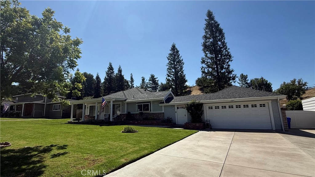Single-story home with stone accents, a two-car garage, wide driveway, and green front lawn.