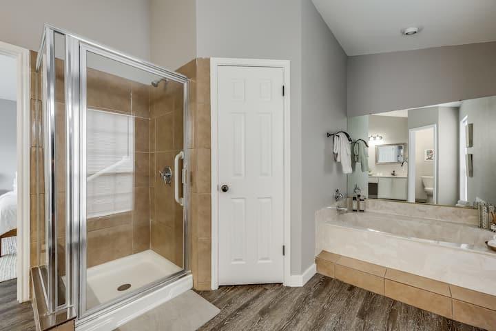 Bathroom with a glass-enclosed tub and shower beside a long mirrored vanity.
