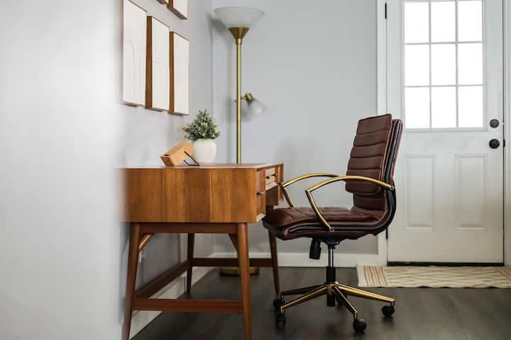 Home office with a wooden desk and brown leather chair beside a glass-paneled door.