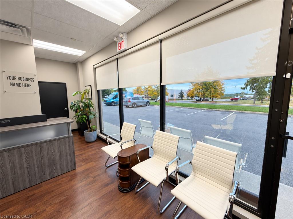 Office reception area with a wood-front desk, cream waiting chairs, and large windows overlooking the street.