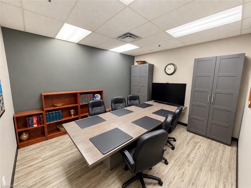 Office conference room with a long table, black chairs, gray cabinets, and wood-look flooring.