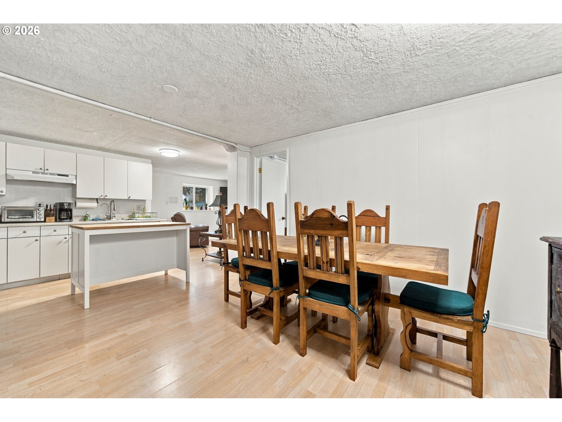 Kitchen and dining area with white cabinets, an island, and a large wooden dining table.