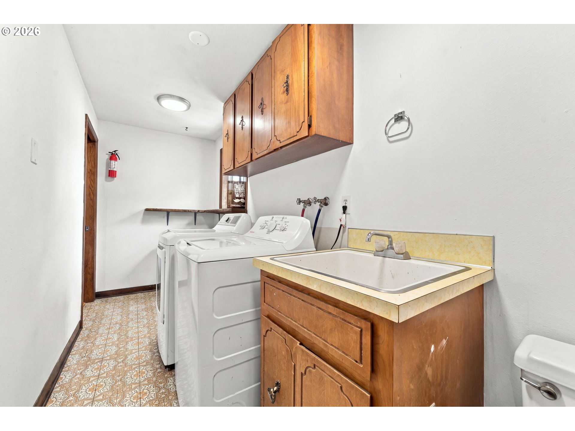 Laundry room with washer and dryer, a deep utility sink, and wood cabinets.