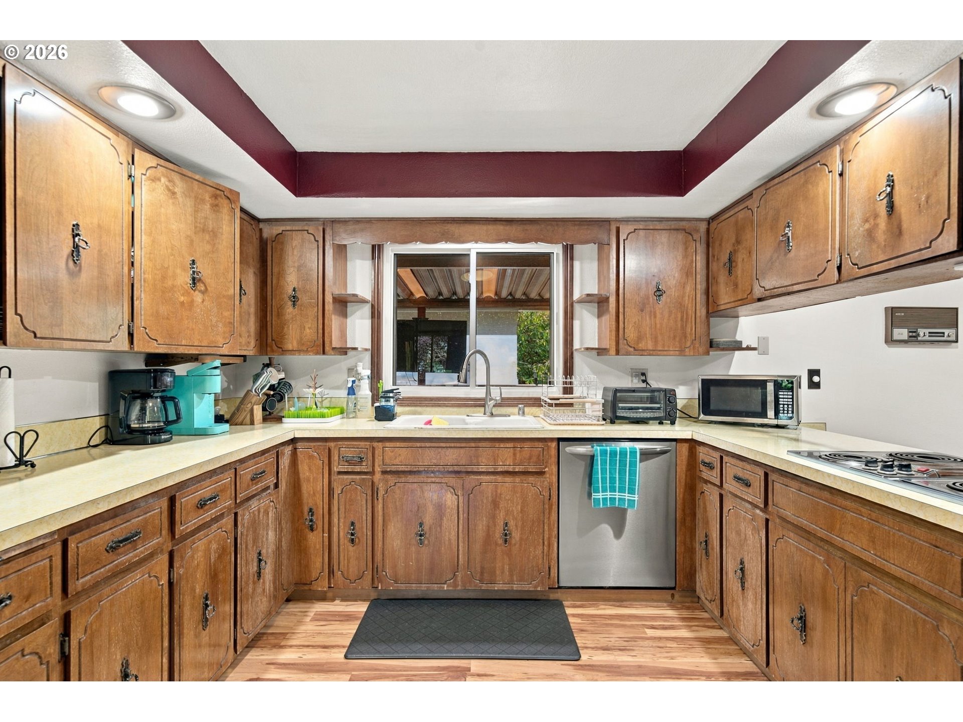 Kitchen with ornate wood cabinets, light countertops, and a window above the sink.