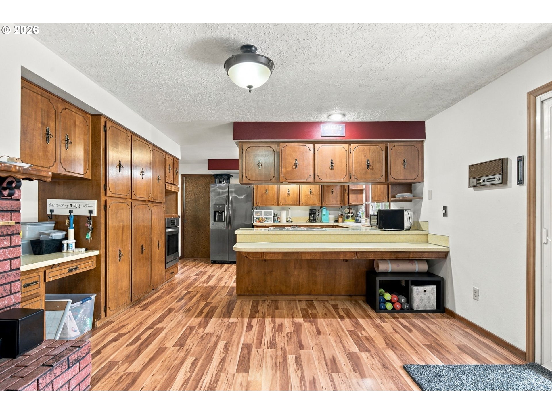 Kitchen with extensive wood cabinetry, a raised breakfast bar, and wood-look flooring.
