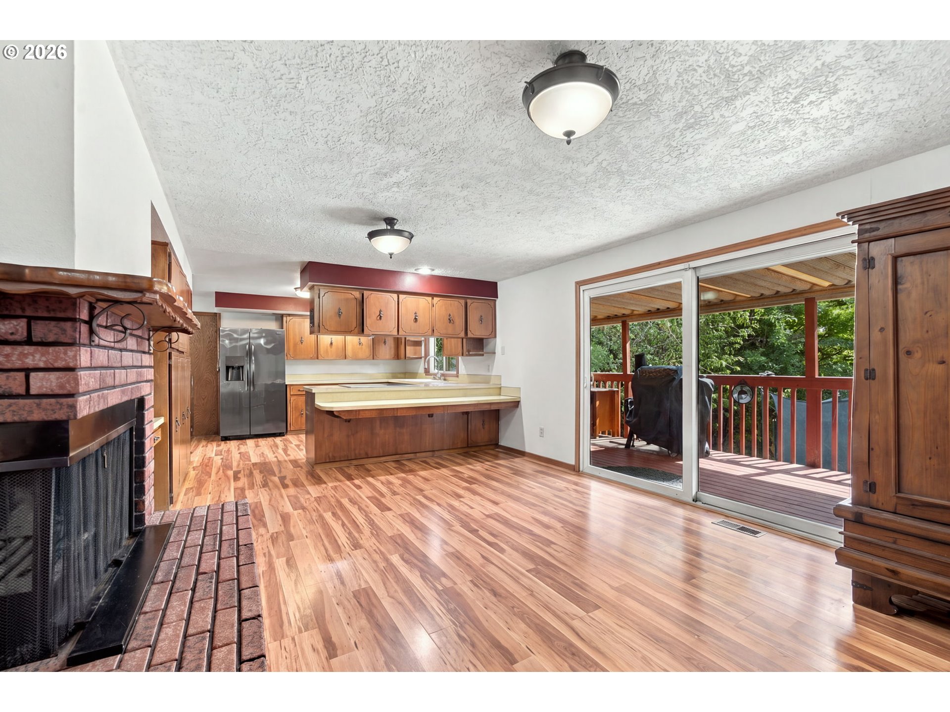 Kitchen and living area with a brick fireplace, wood cabinetry, and sliding doors to a covered deck.