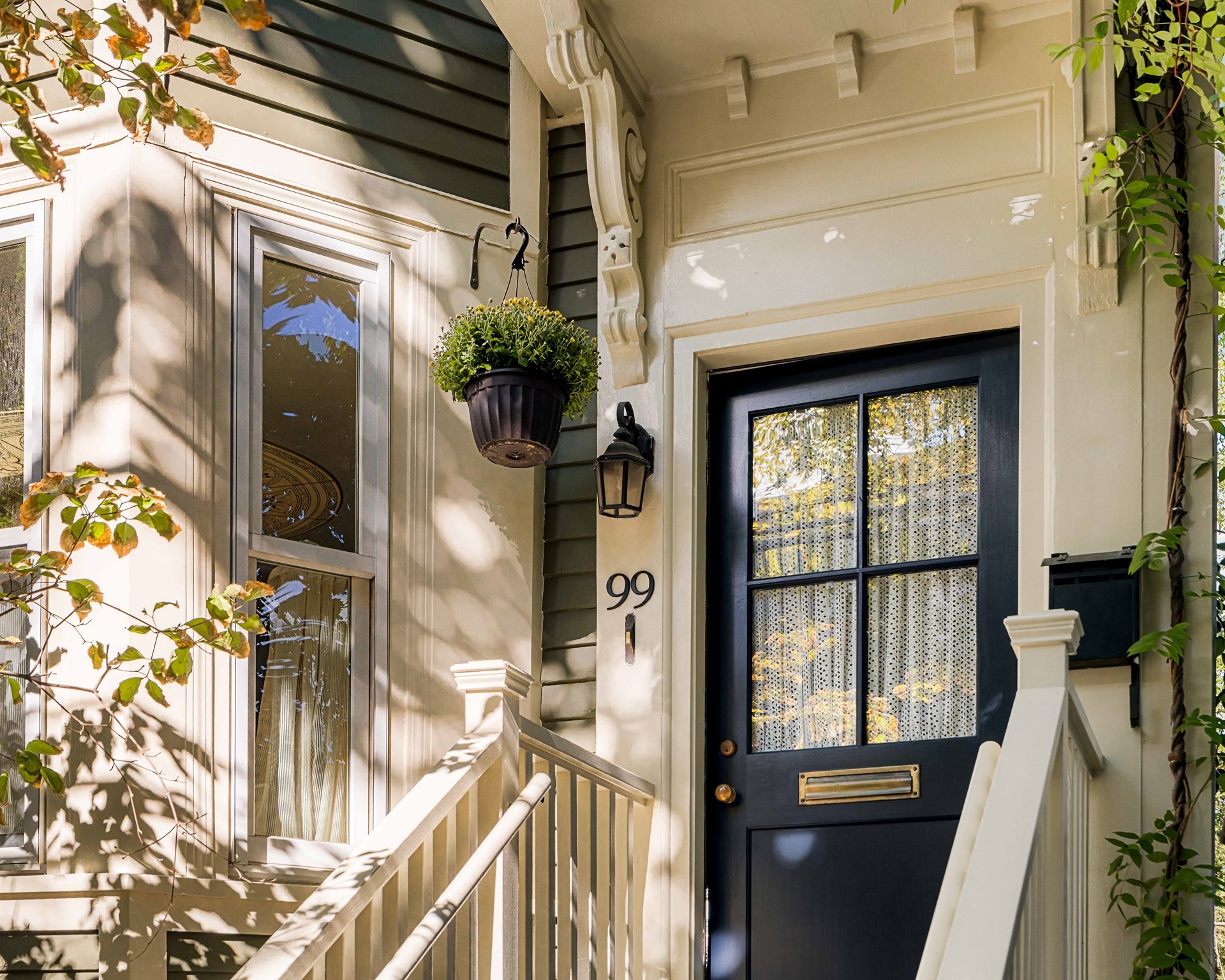 Home entrance with a dark blue divided-light door, white porch trim, and house number 99.