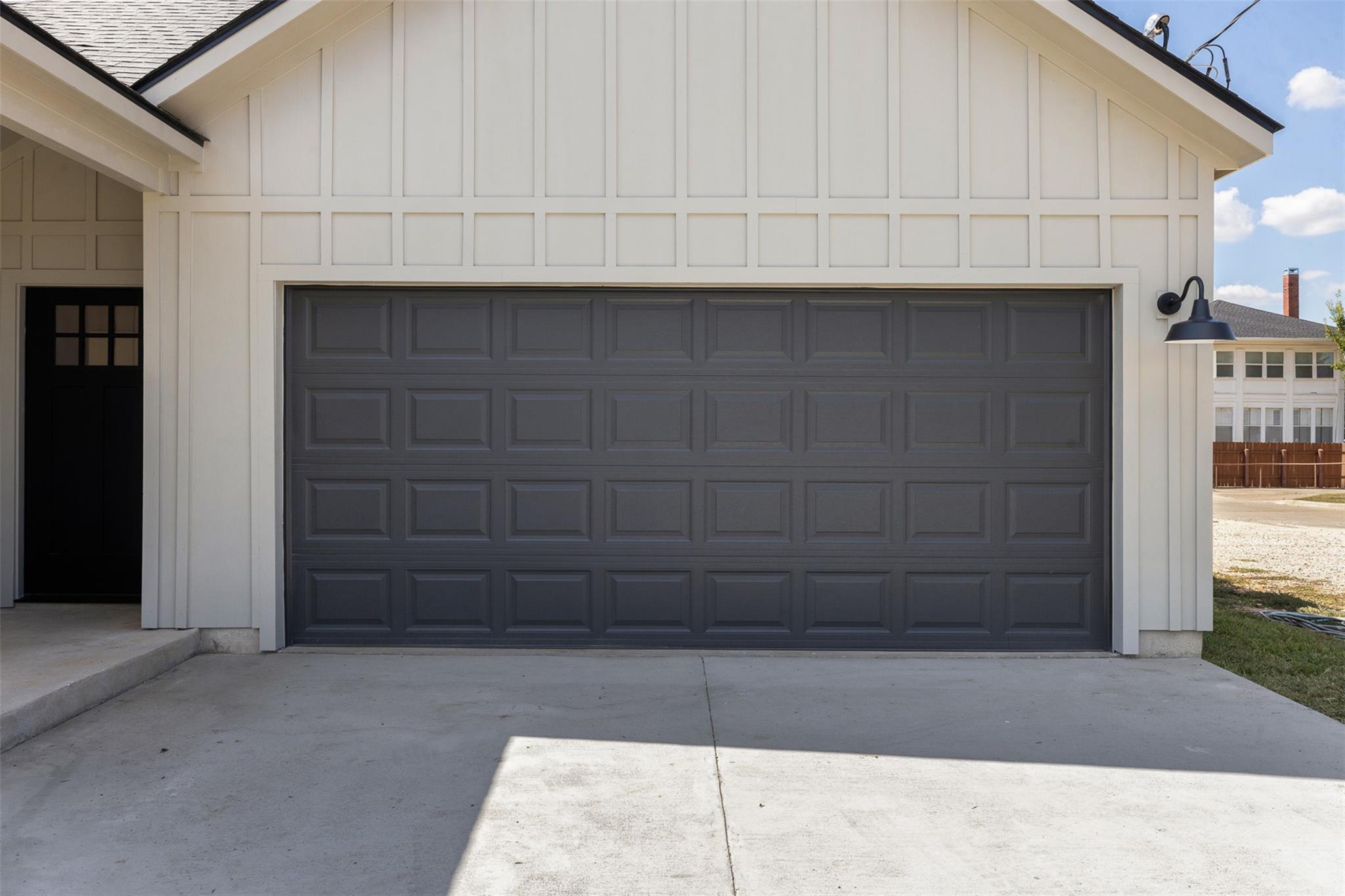 Home exterior with a dark double garage door, board-and-batten siding, and a concrete driveway.