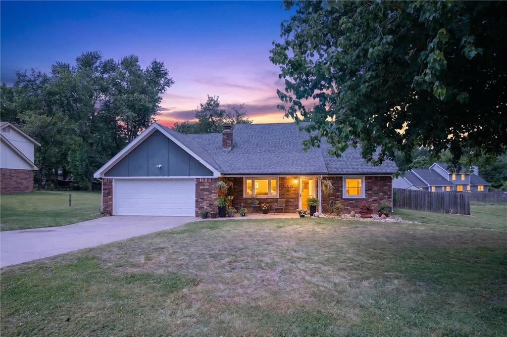 Brick ranch home with an attached garage and warmly lit windows at dusk.