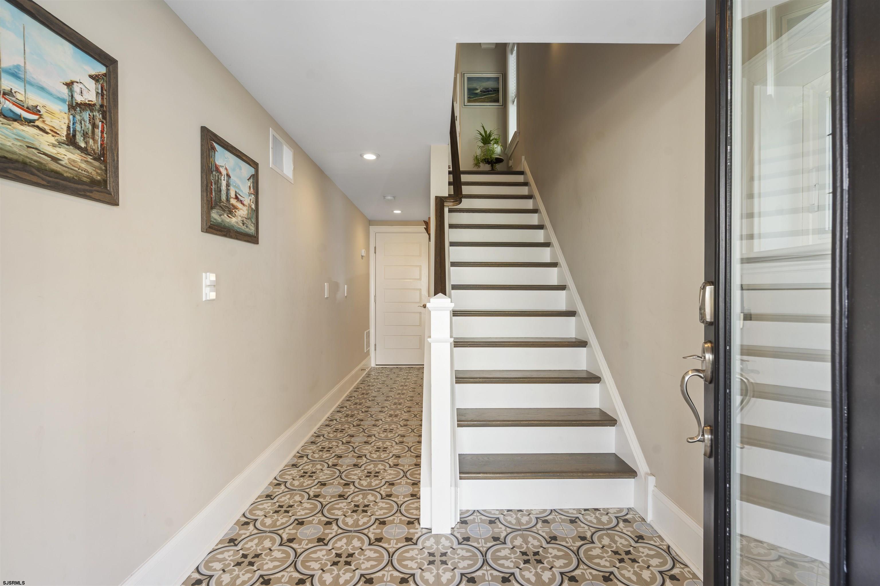 Entry hall with patterned tile floor and a white staircase with dark wood treads.