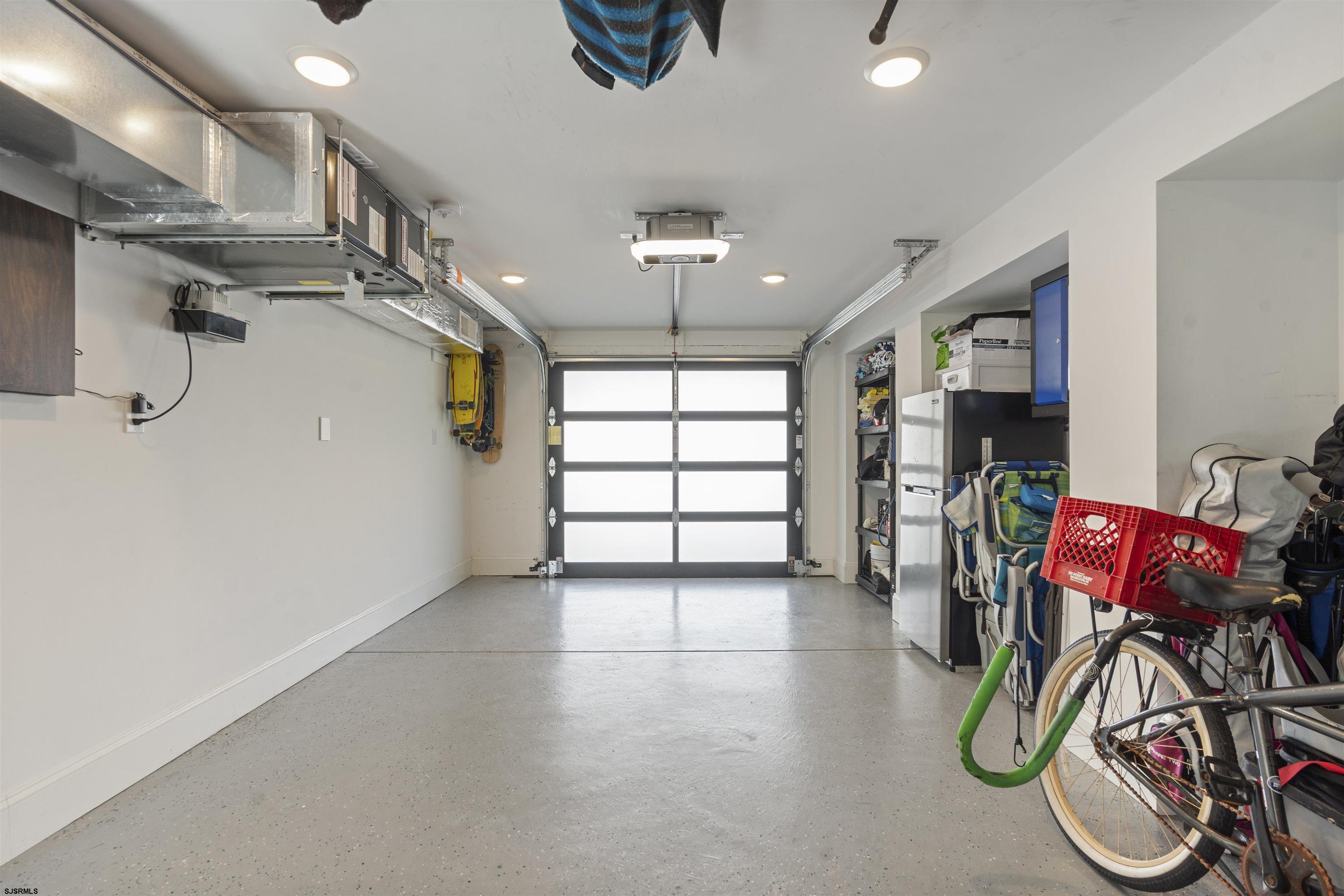 Garage with a frosted-panel door, overhead storage, and bicycles and beach gear along one side.