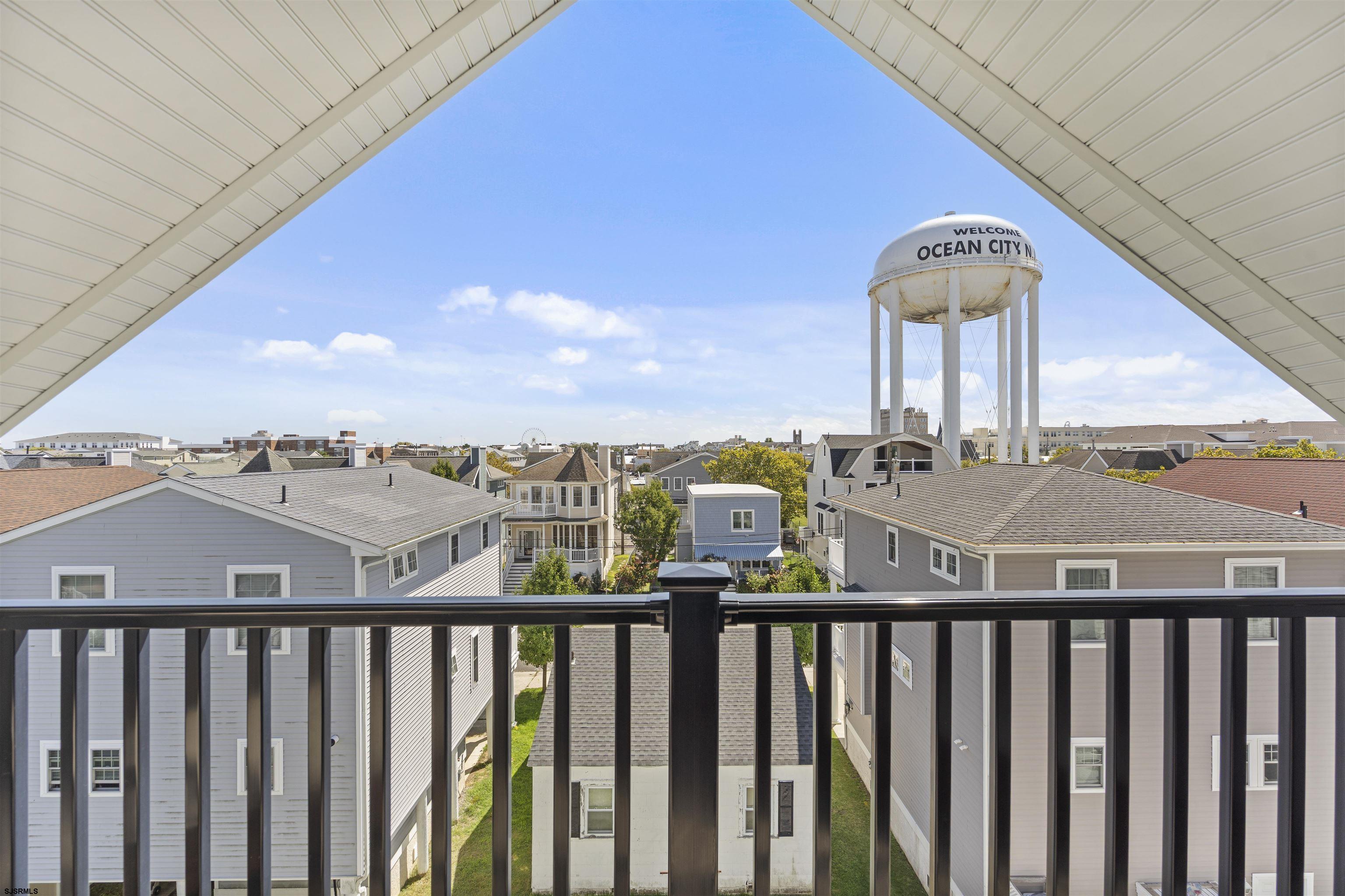 Balcony view over Ocean City rooftops, framed by a peaked roof with the town’s water tower in the distance.