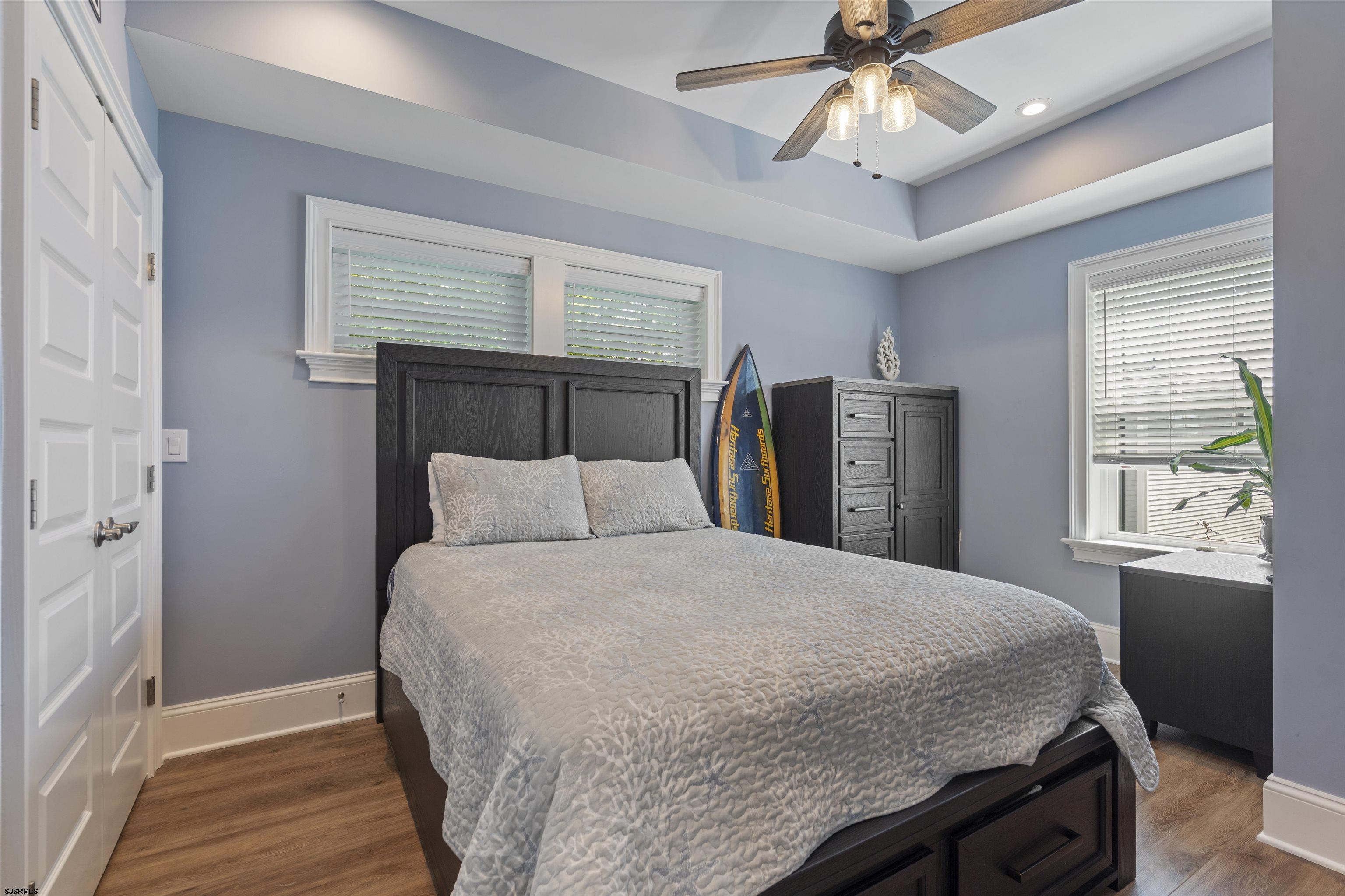 Bedroom with a dark wood bed, blue-gray walls, and surfboards beside the dresser.