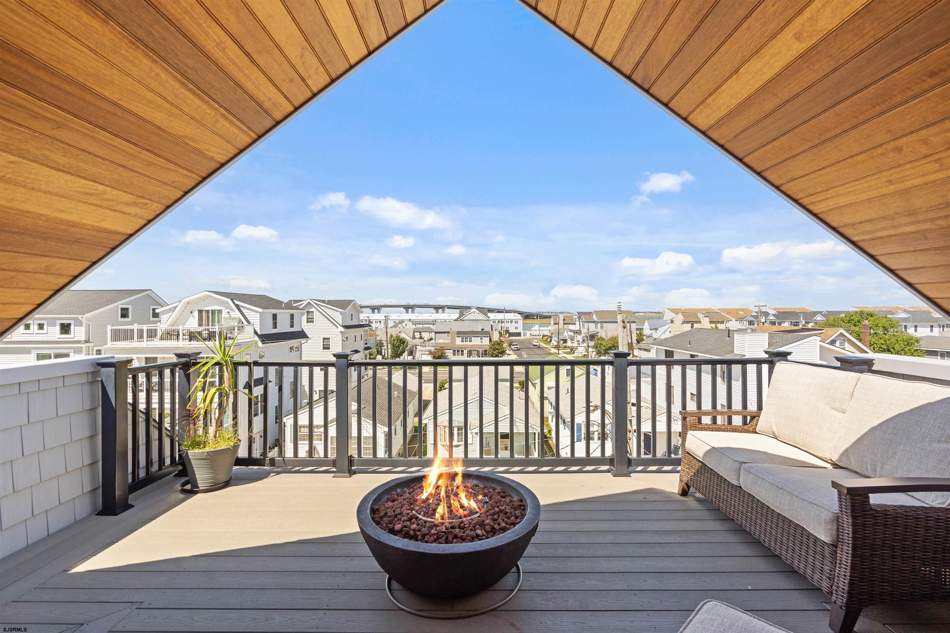 Rooftop deck with a fire pit and wicker sofa overlooking Ocean City homes.