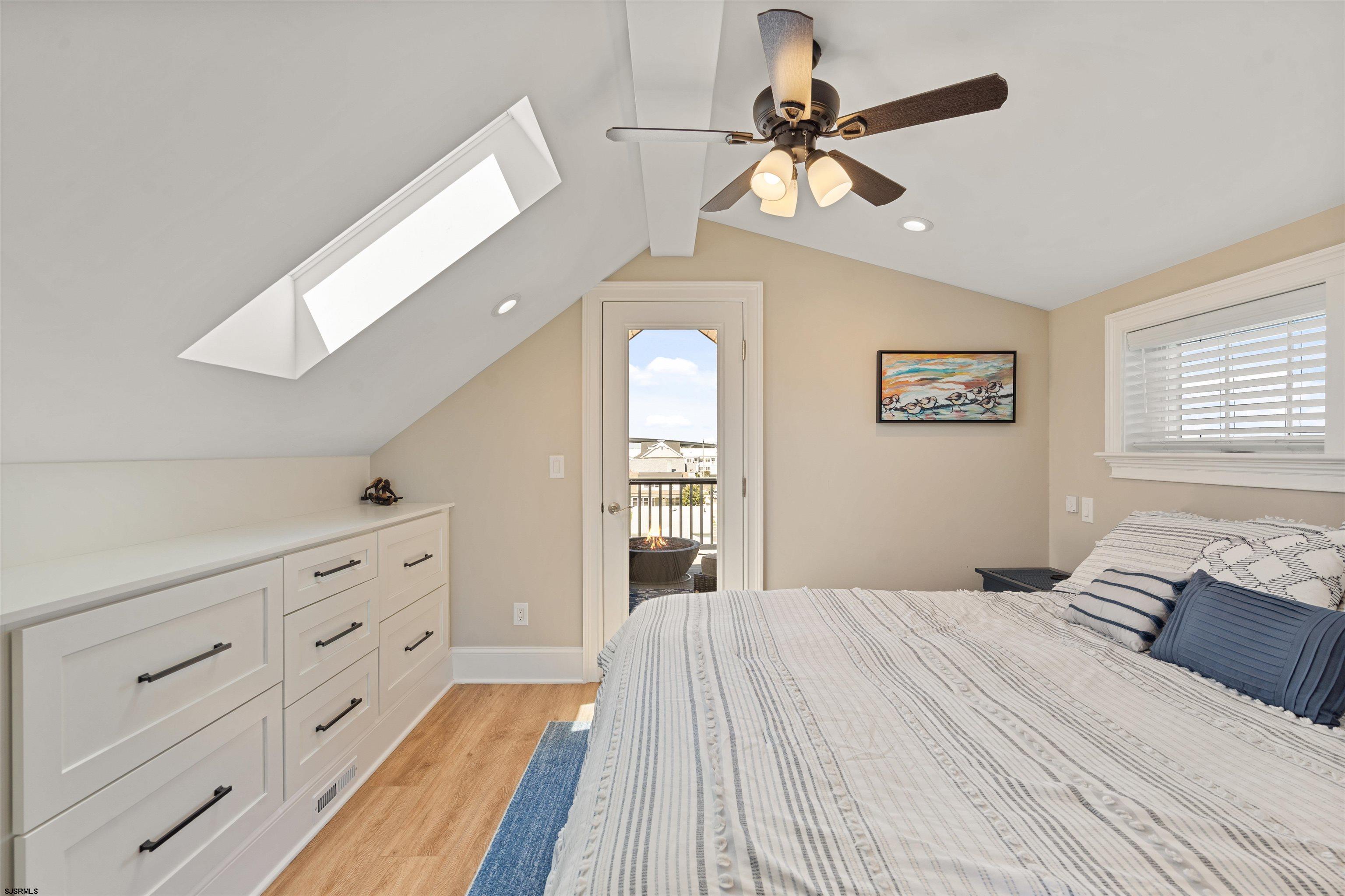 Bedroom with striped bedding, built-in drawers, a skylight, and a balcony door.