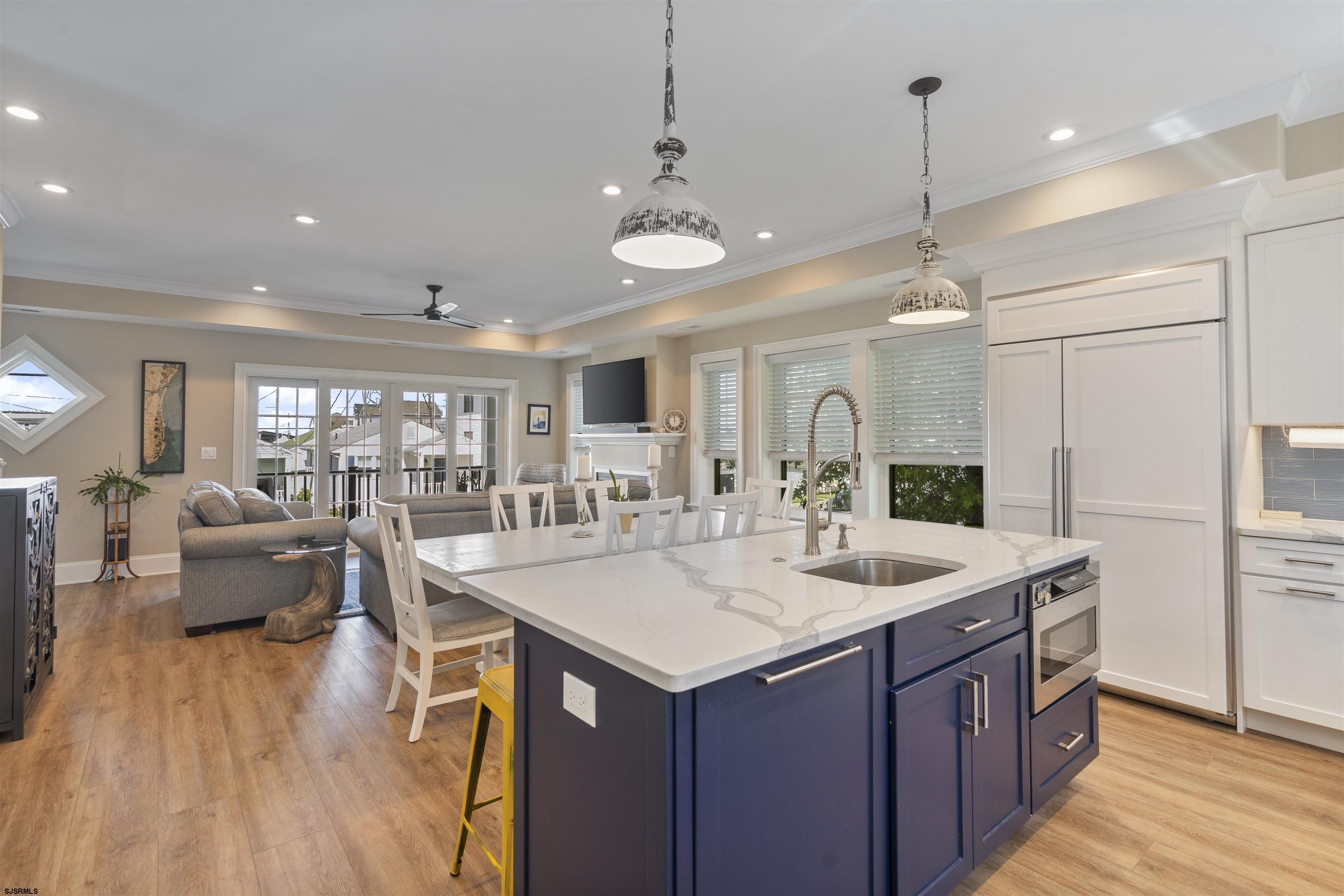 Open-plan kitchen with a large navy island, white stone countertop, and adjoining living and dining areas.