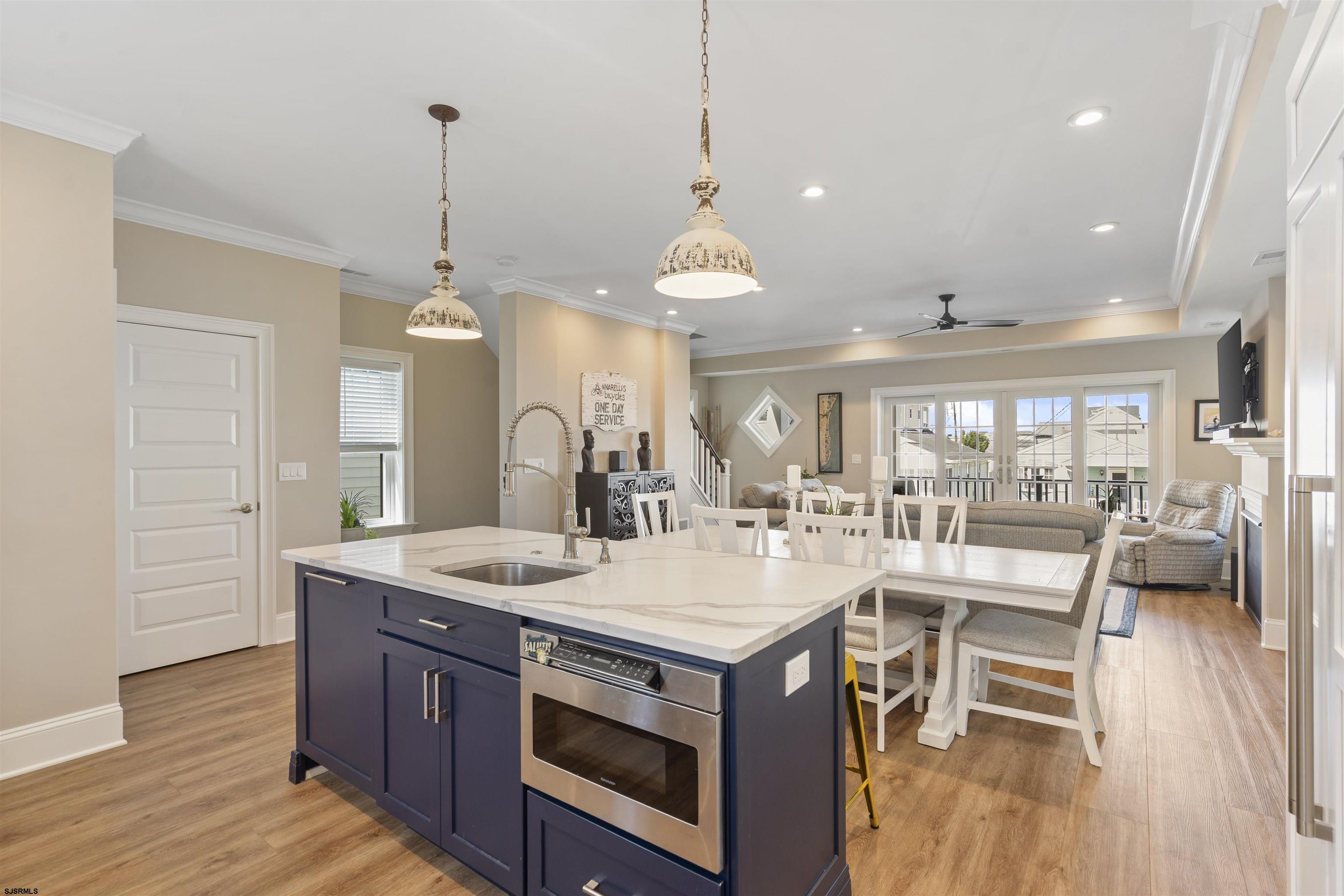Open-plan kitchen with a navy island, white stone countertop, and dining and living areas beyond.