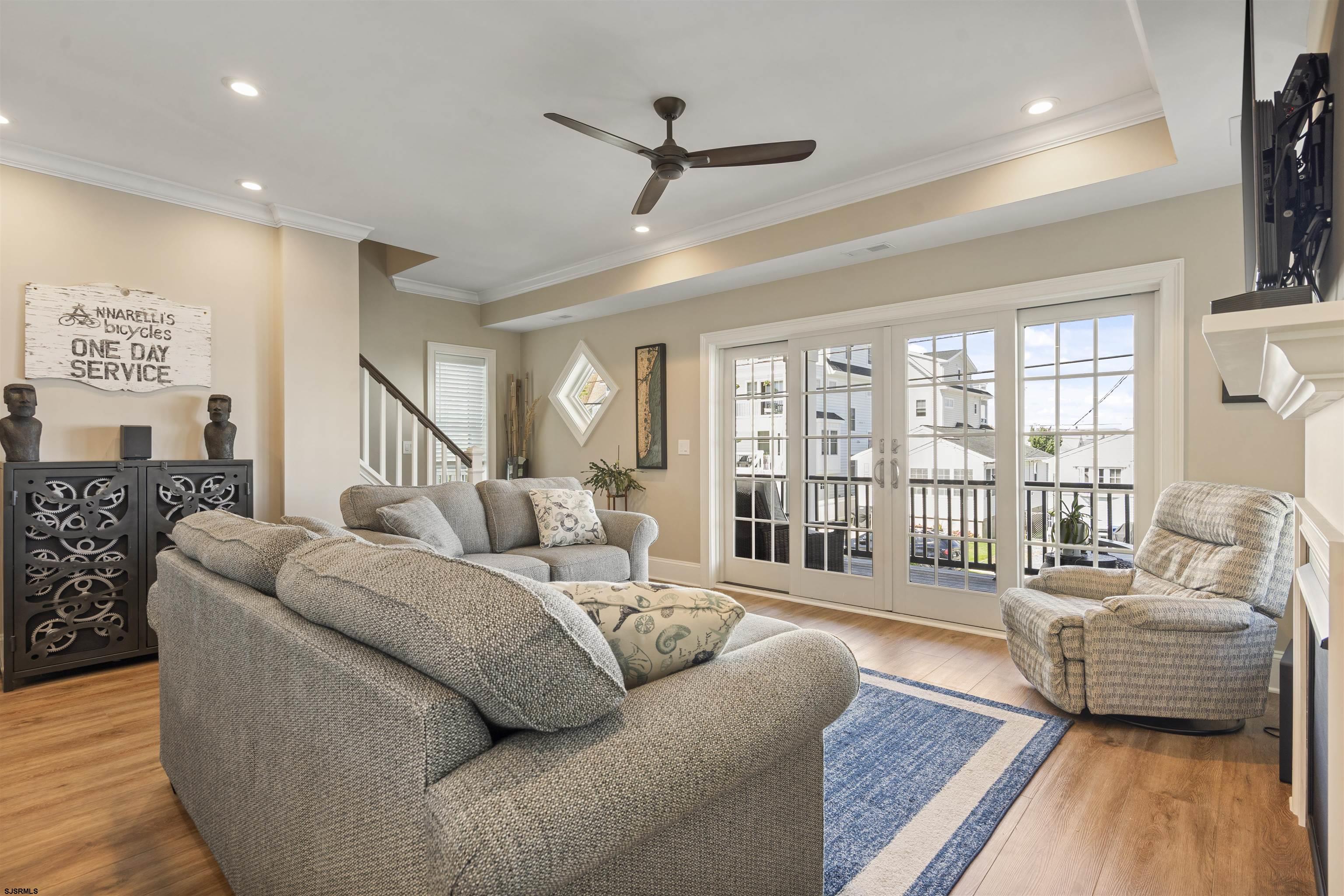 Living room with a gray sectional, recliner, blue rug, and French doors to a balcony.