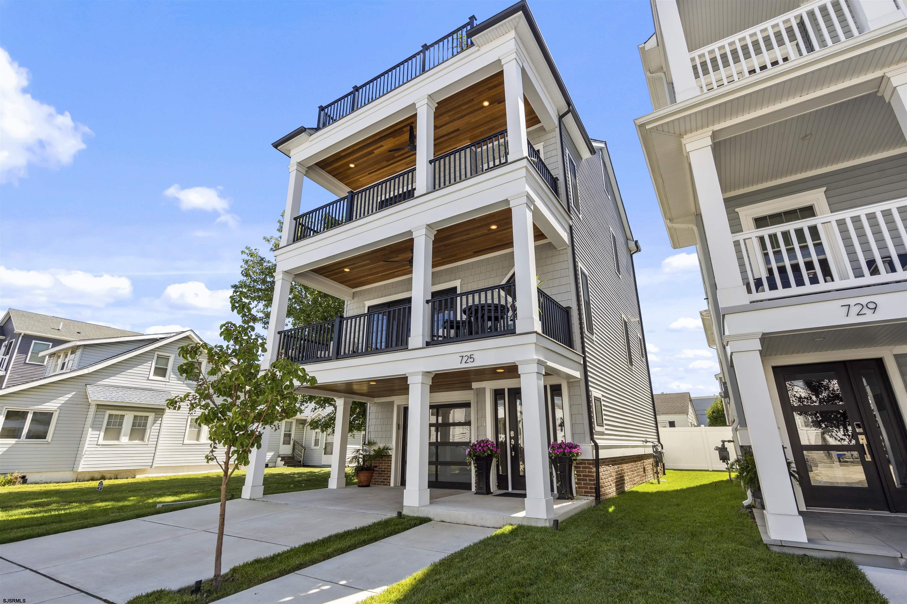 Three-story home at 725 with stacked covered balconies, black railings, and warm wood ceilings.