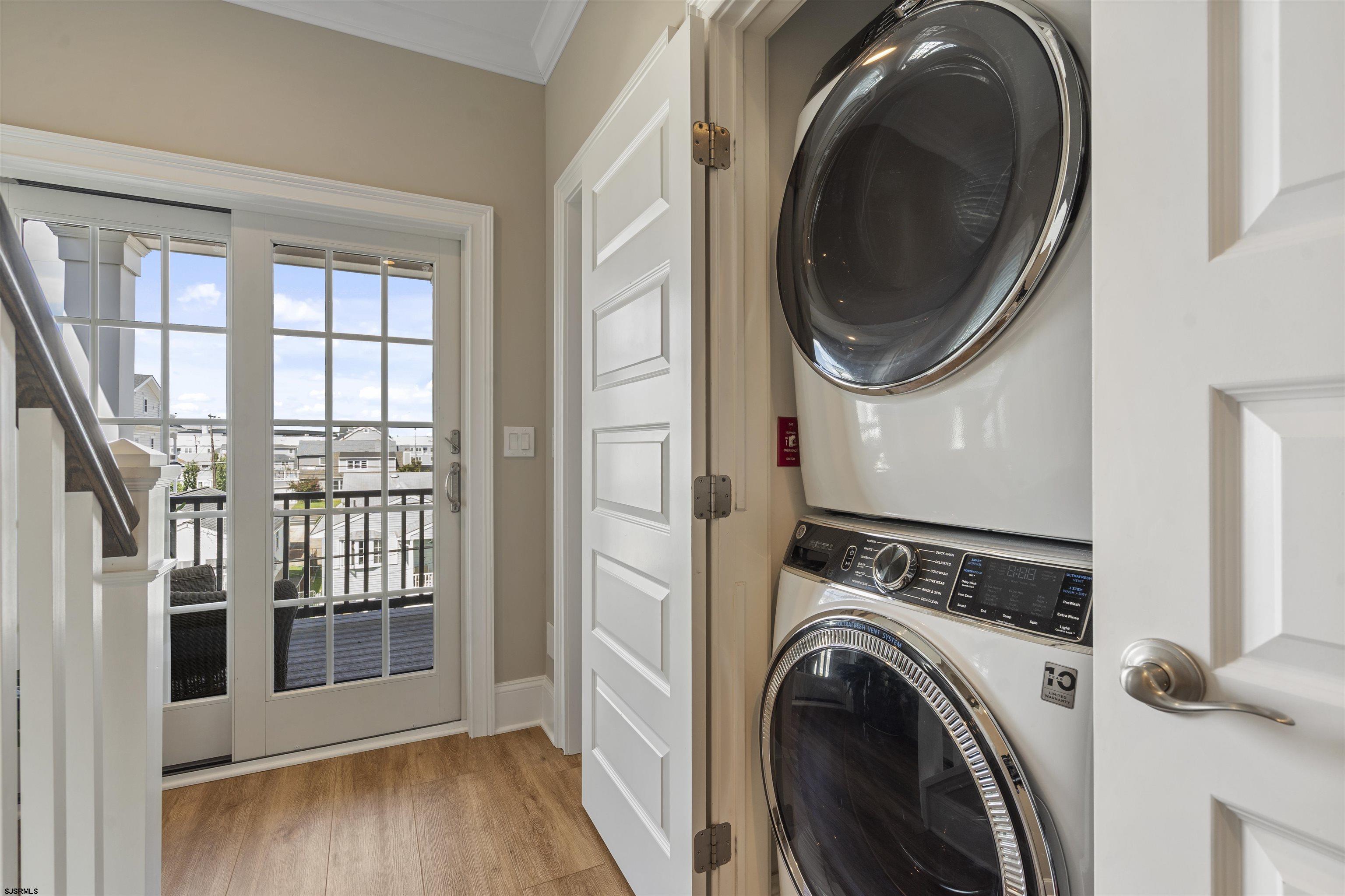 Laundry area with stacked washer and dryer beside a glass door opening to a balcony.