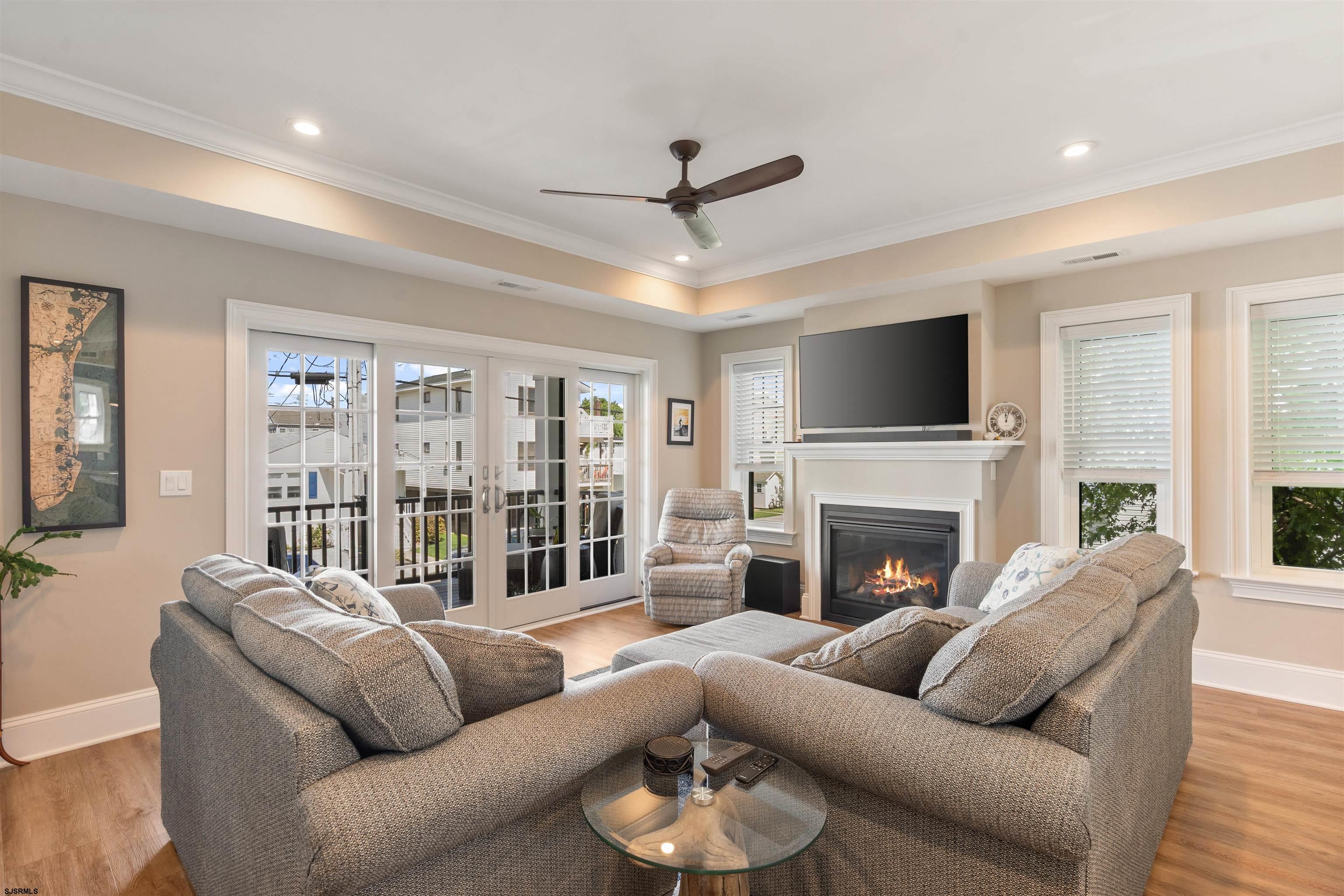 Living room with a large sectional sofa, fireplace, and French doors opening to a deck.