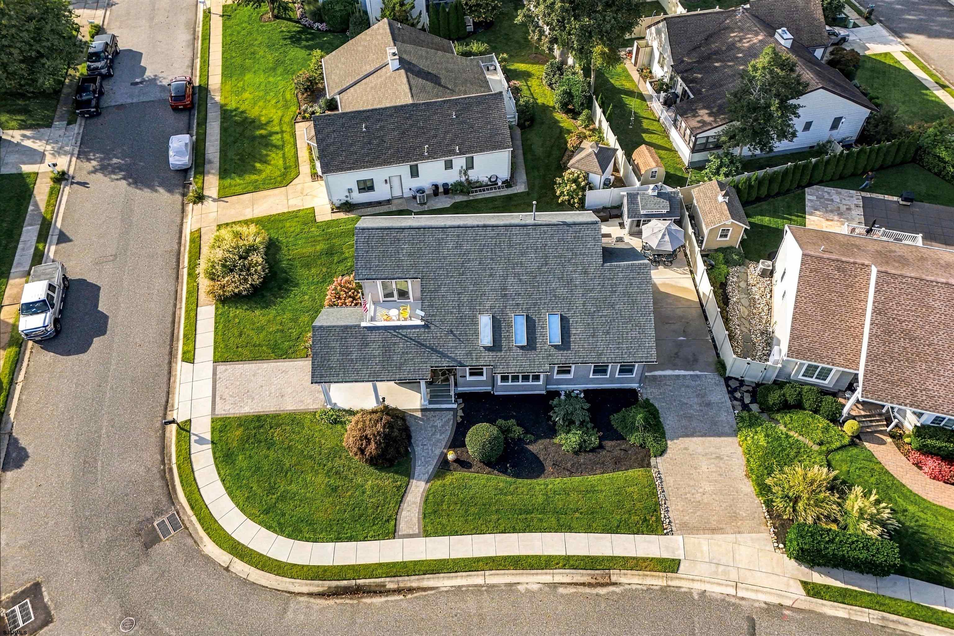 Aerial view of 415 Portsmouth Road, a gray-roofed home on a landscaped corner lot with a curved sidewalk.