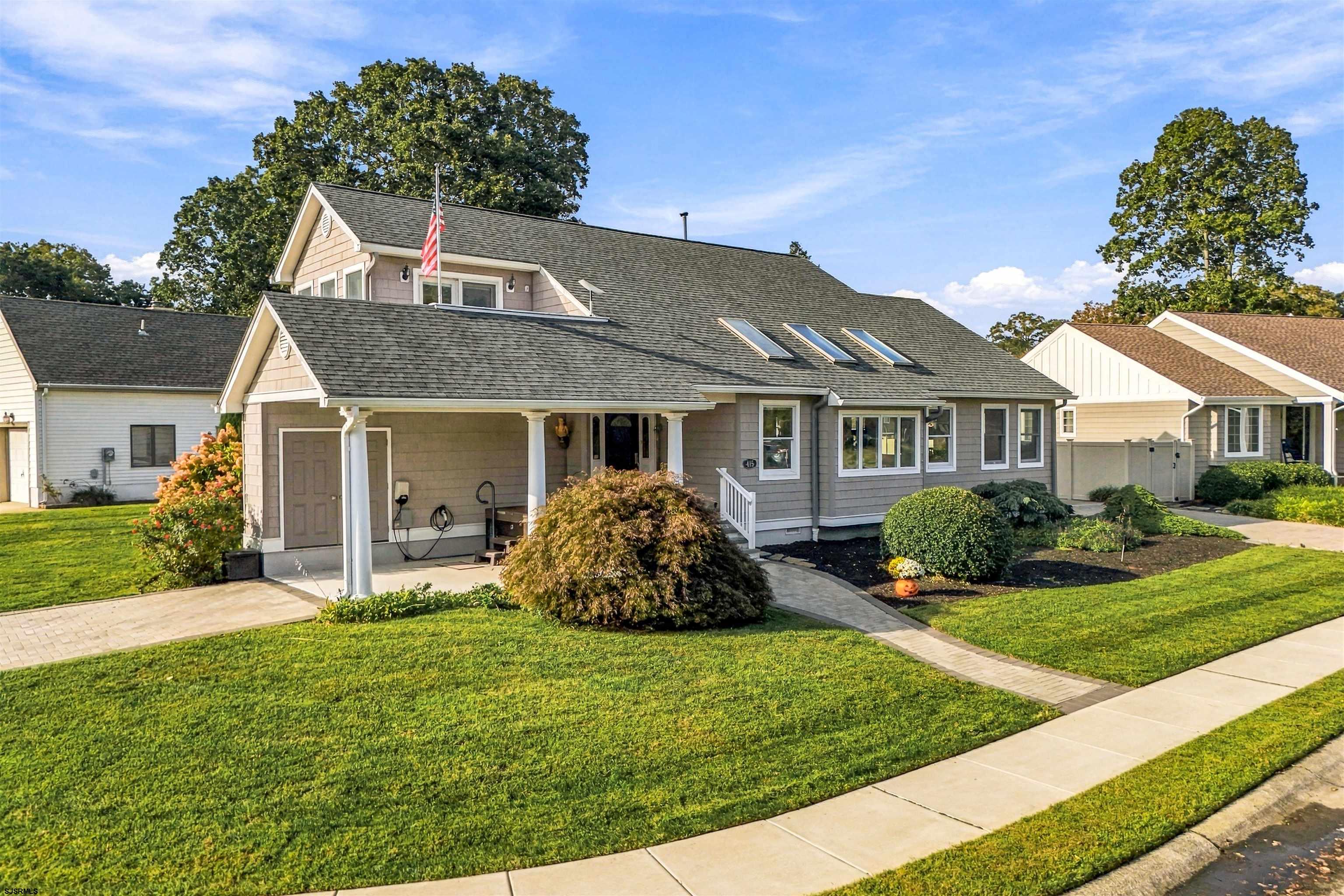 Gray home with a covered entry, three roof skylights, and landscaped lawn.