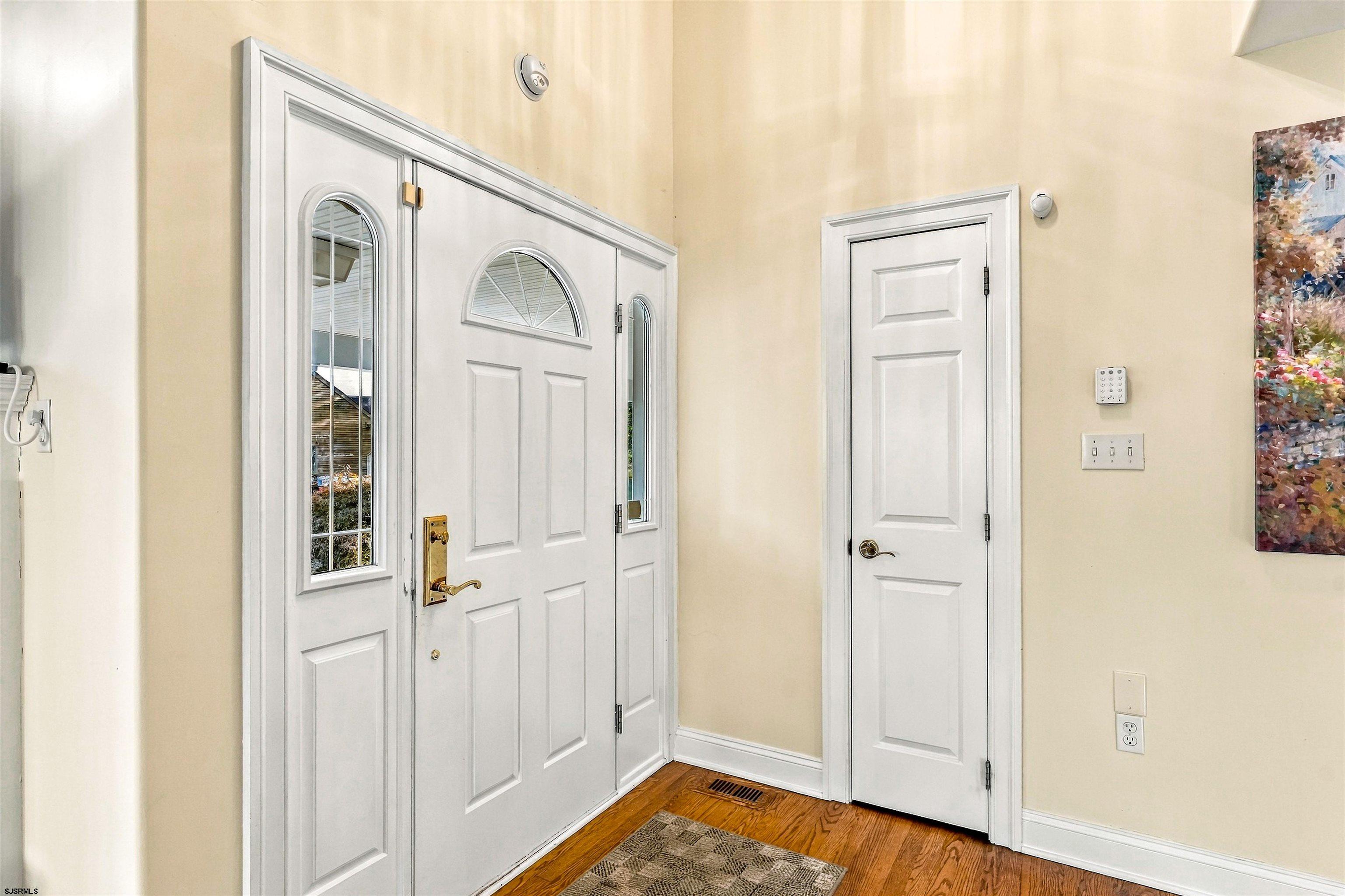 Entry foyer with a white front door, fanlight, sidelights, and hardwood floor.