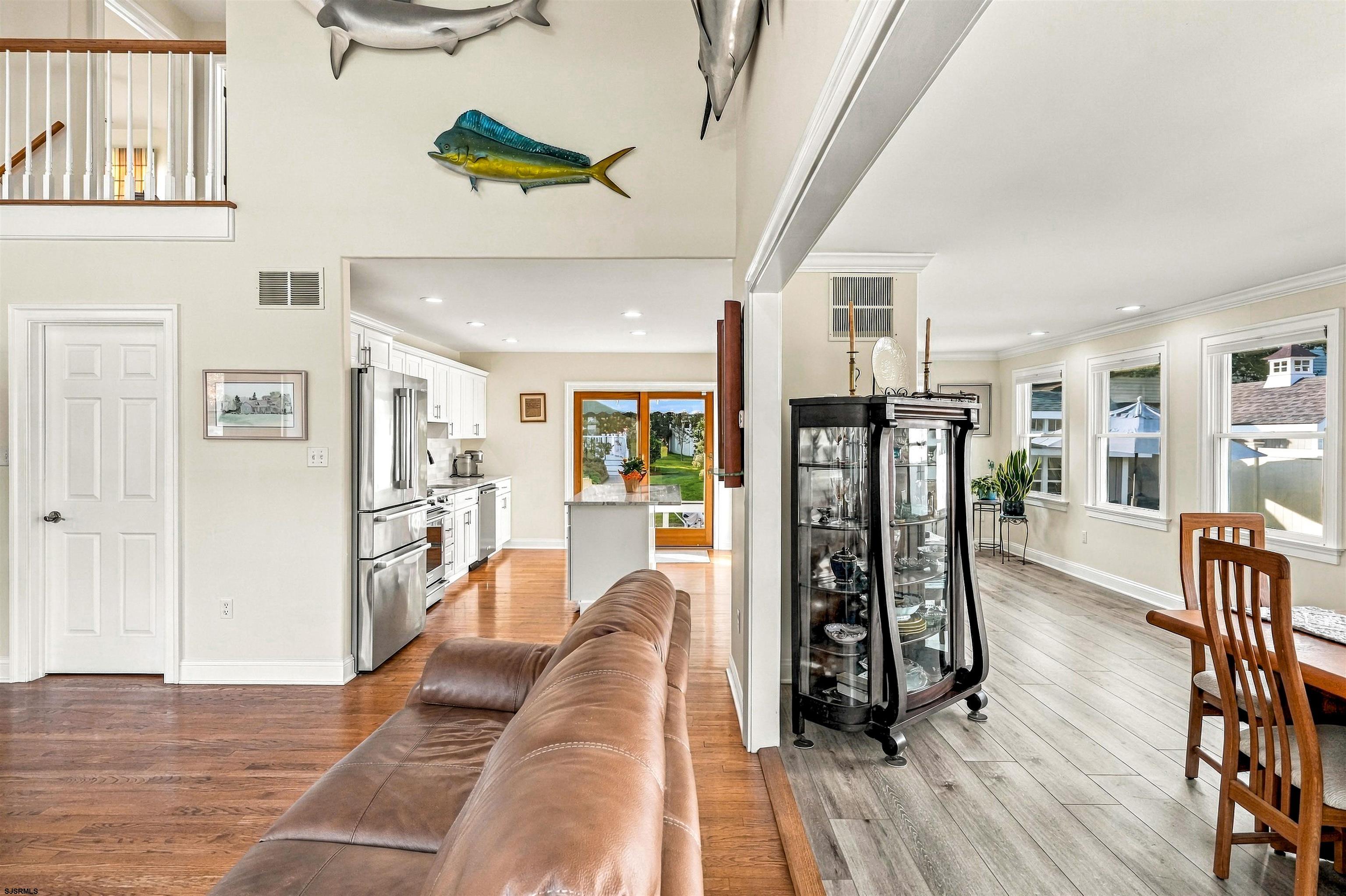 Open-plan living room, kitchen, and dining area with a leather sofa and water visible through the back doors.