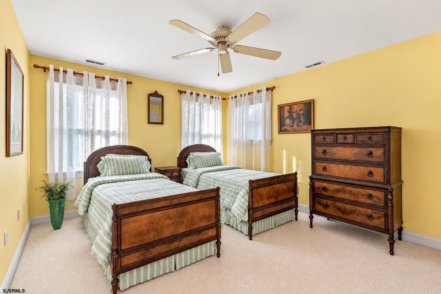 Bedroom with two wooden twin beds, striped bedding, and a large matching dresser.