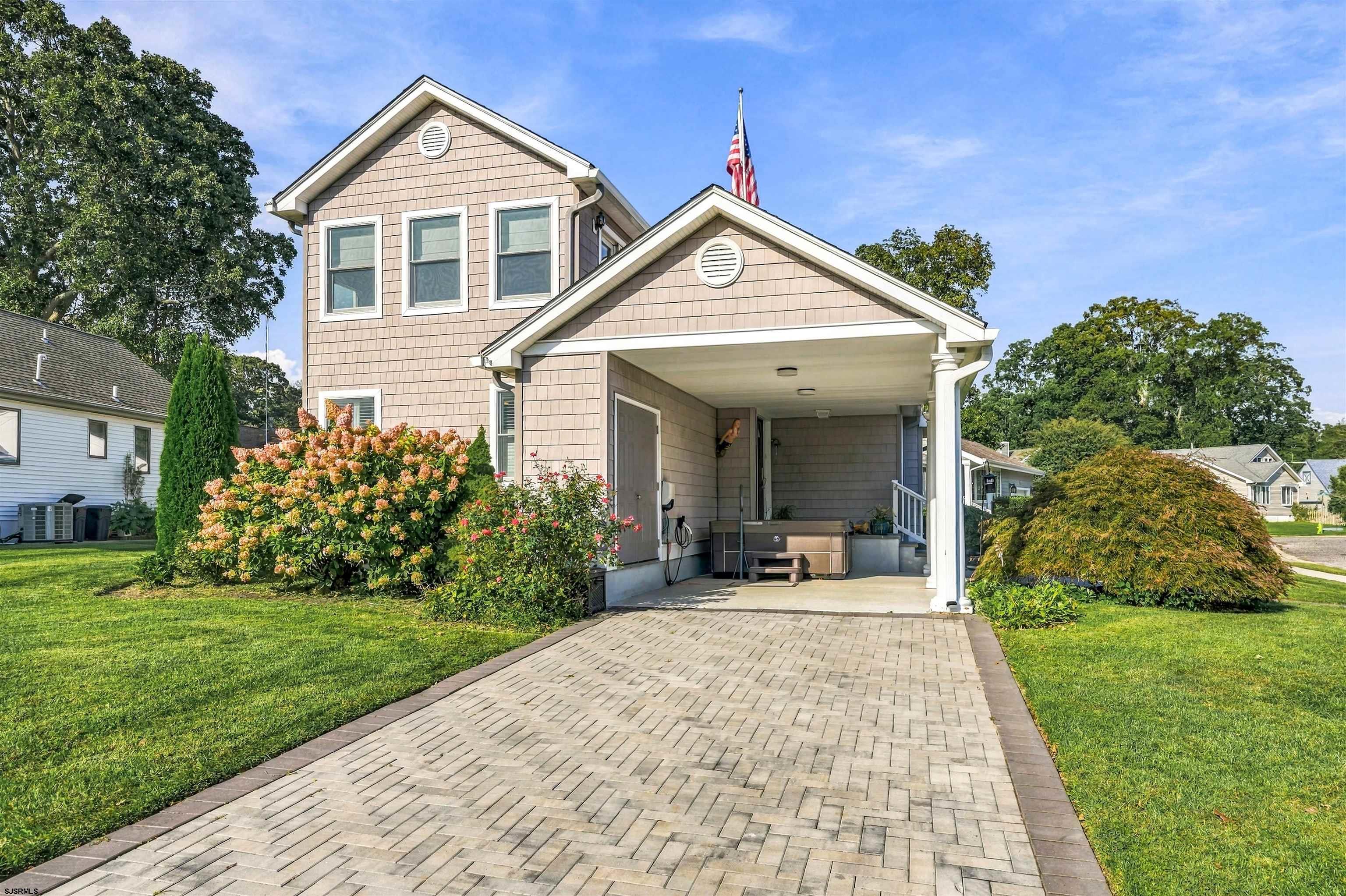 Two-story home with a paved driveway, covered porch, hot tub, and landscaped front yard.