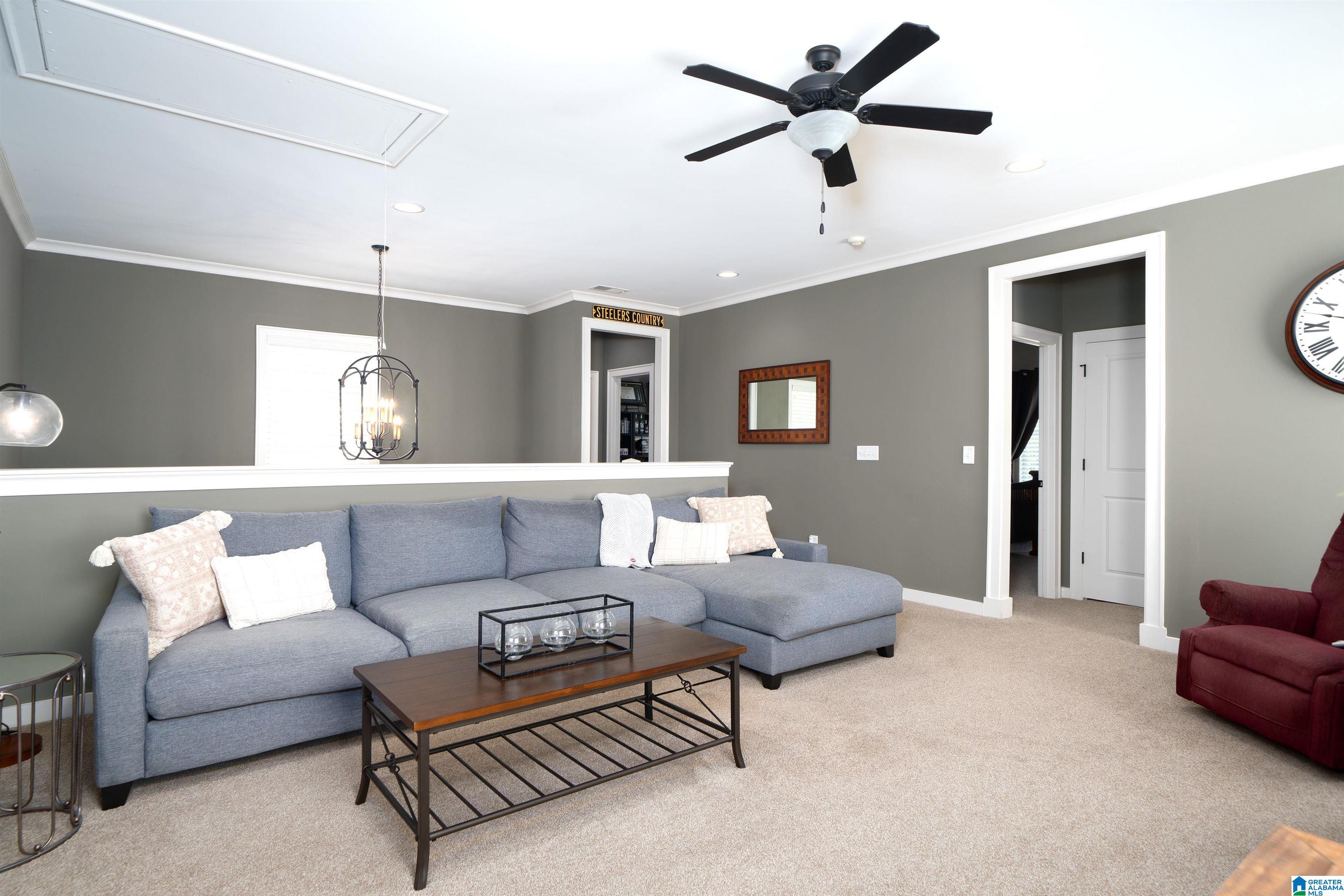 Furnished living room with a gray sectional, wooden coffee table, and red armchair.