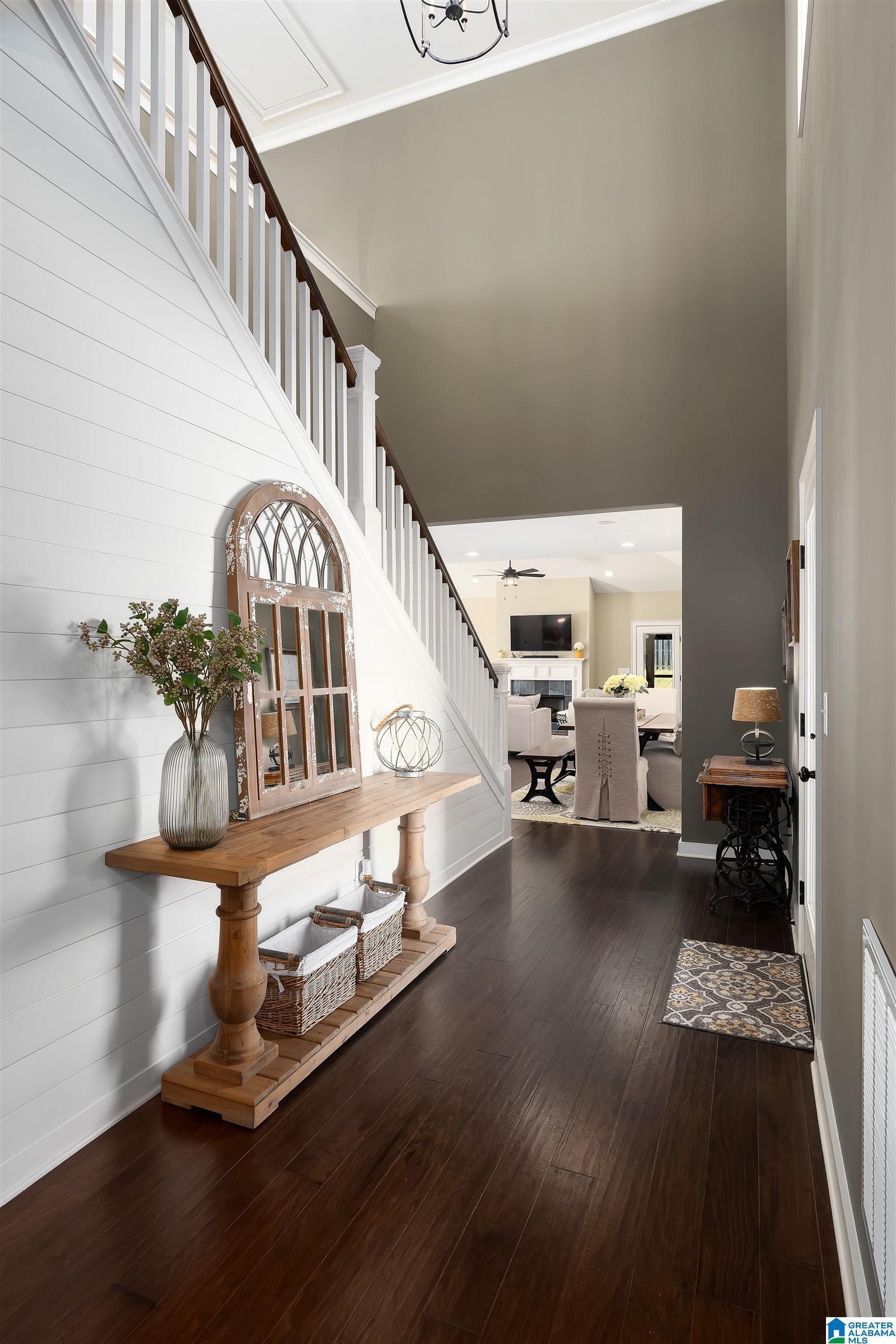 Entry foyer with a white staircase, dark wood floors, and a rustic console table beneath the stairs.