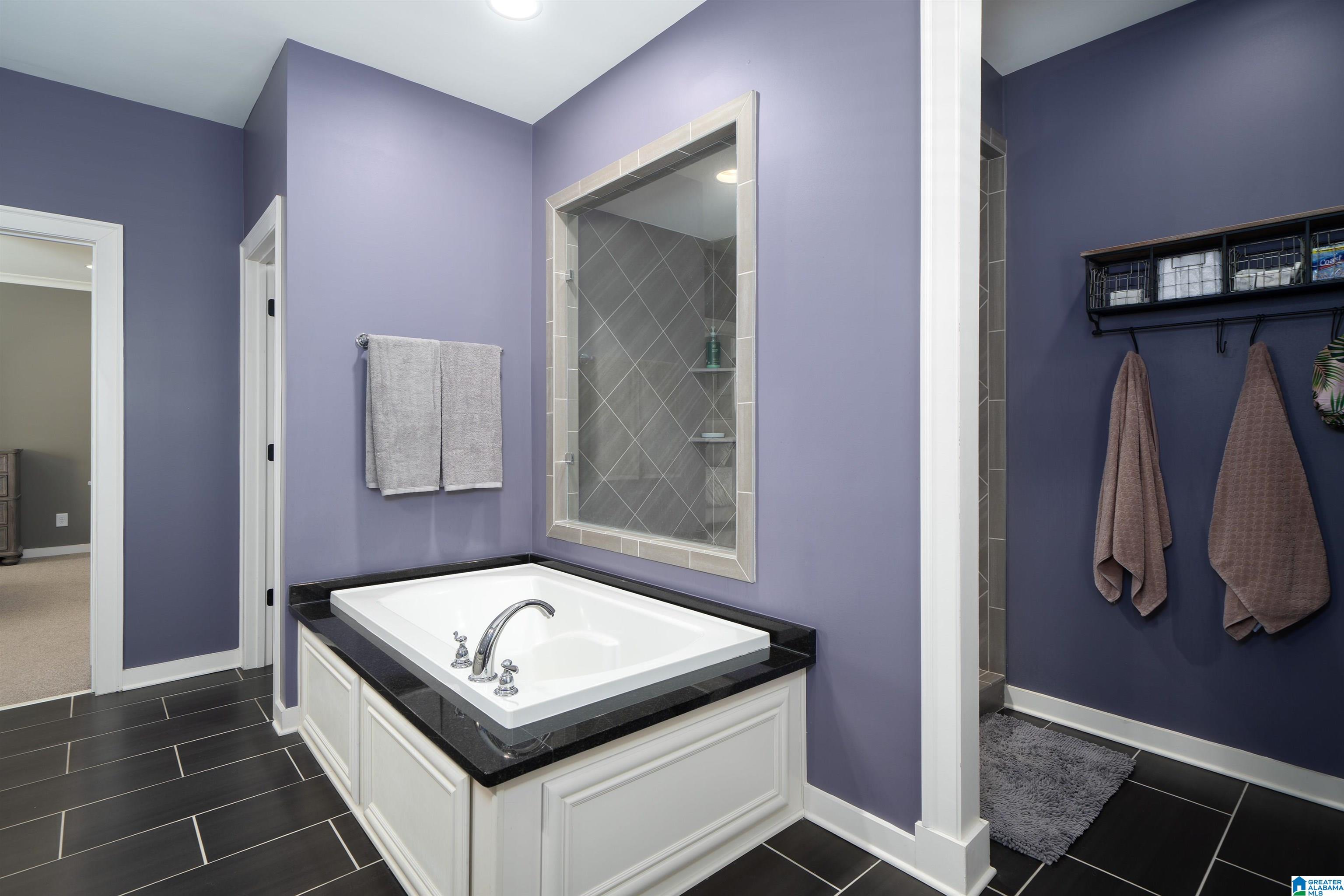 Bathroom with a built-in soaking tub and glass-enclosed tiled shower.