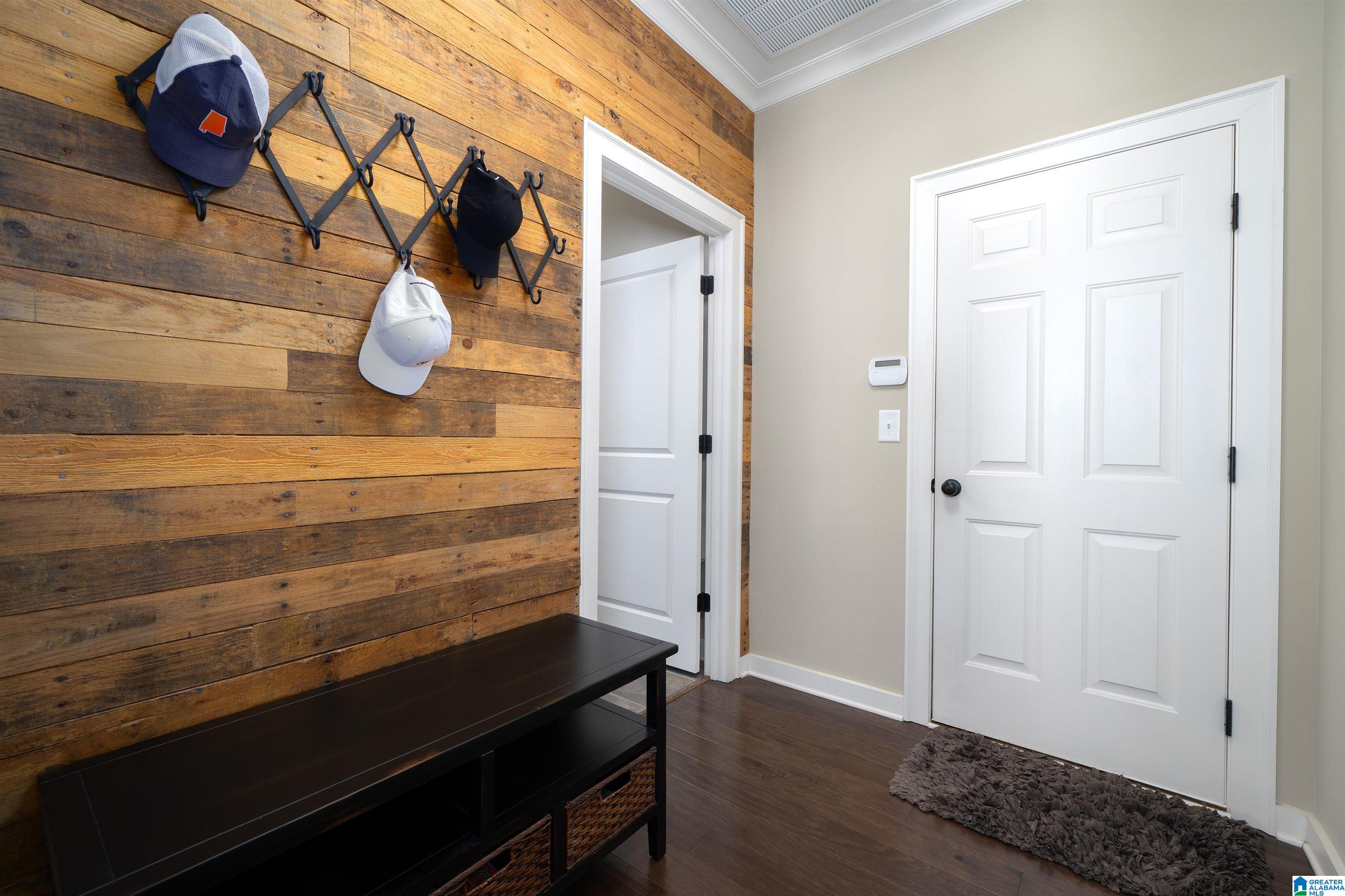 Entryway with a reclaimed wood wall, mounted coat rack, black bench, and white paneled doors.
