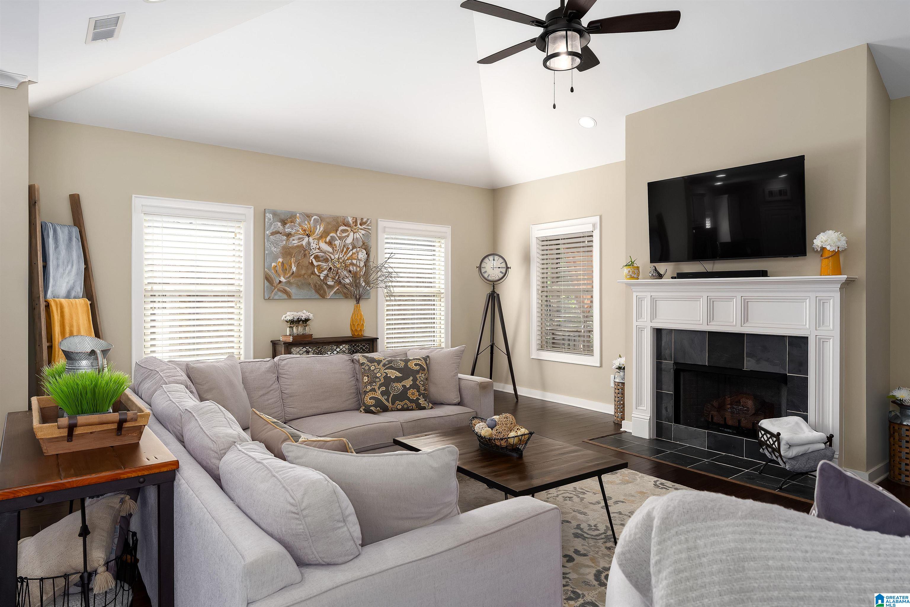 Furnished living room with a gray sectional, white fireplace, and wall-mounted television.