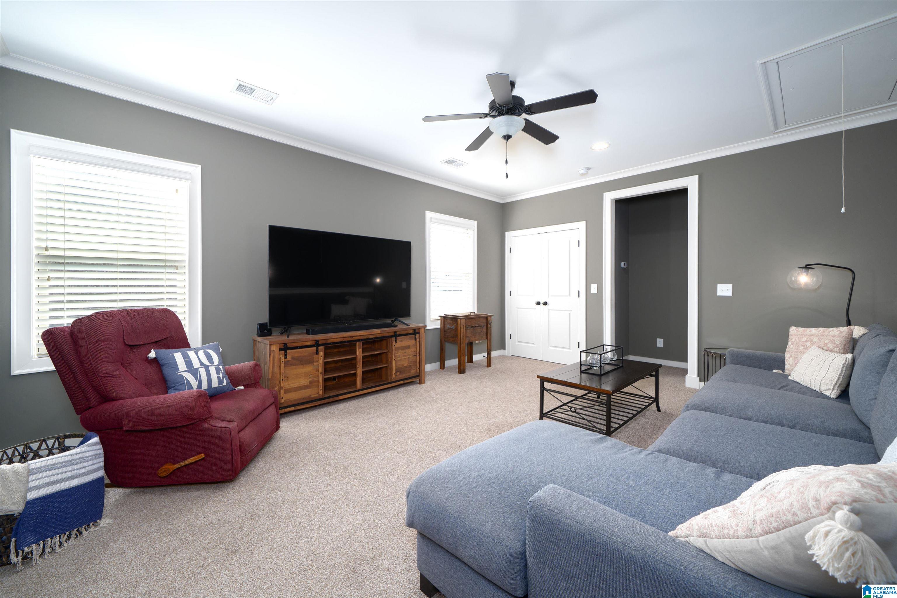 Living room with a blue sectional, burgundy recliner, and television on a wooden console.