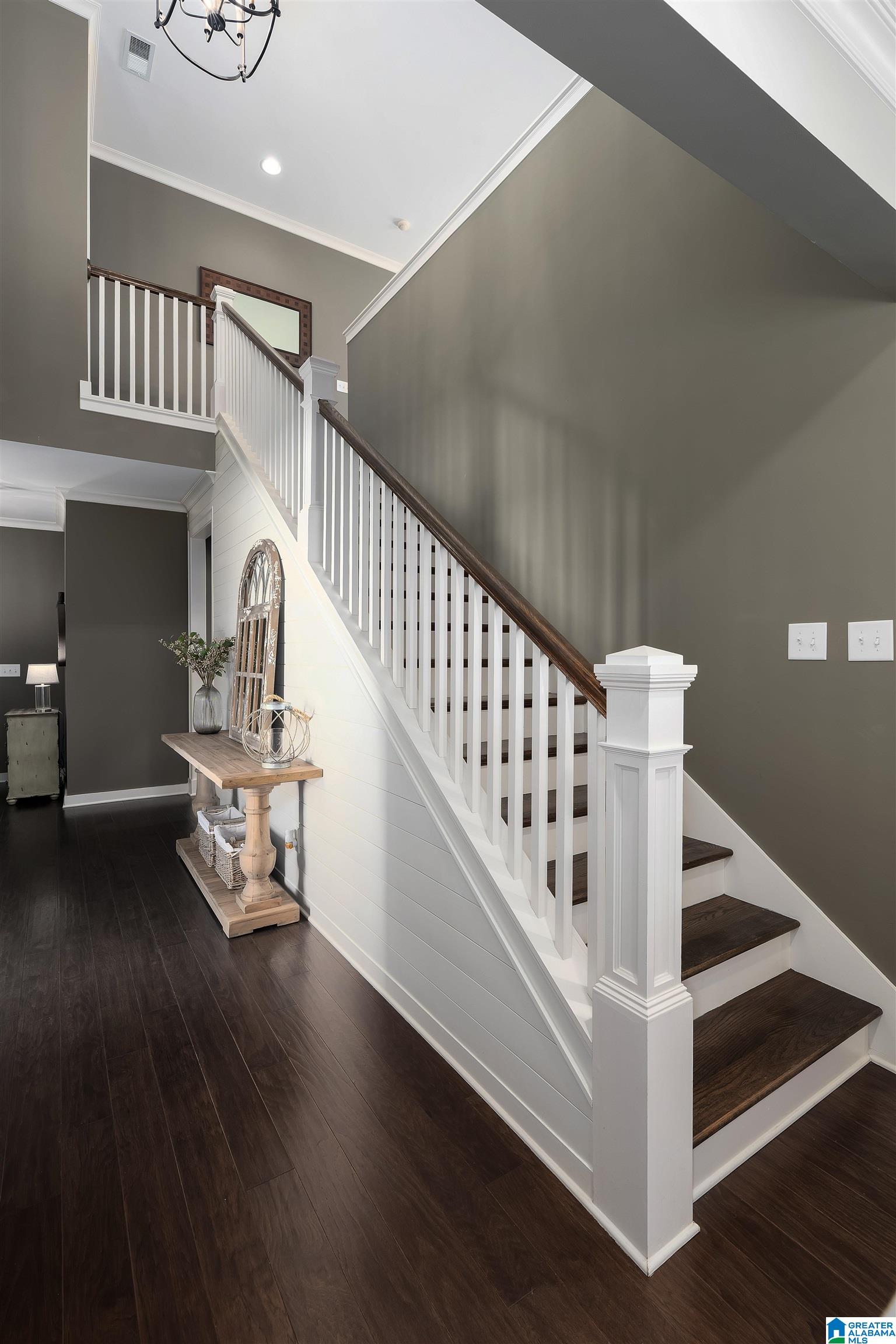 Foyer with a white staircase, dark wood treads, and a console table beneath the stairs.