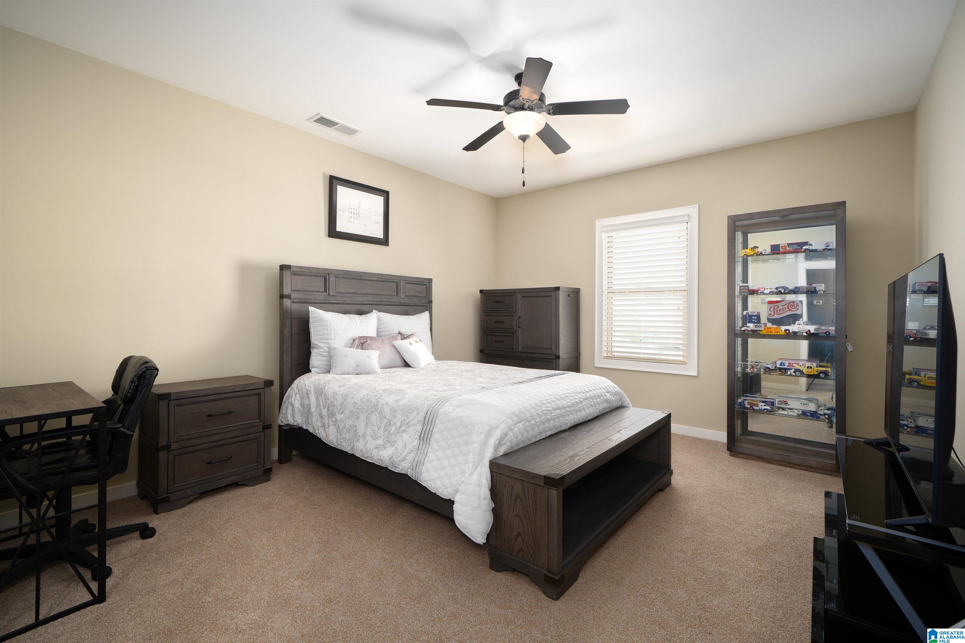 Furnished bedroom with dark wood furniture and a glass cabinet displaying model vehicles.