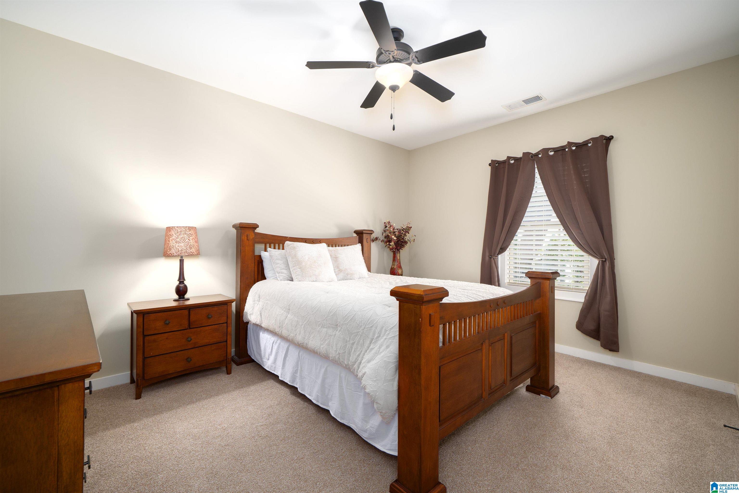 Furnished bedroom with a wooden four-poster bed, white bedding, and a curtained window.
