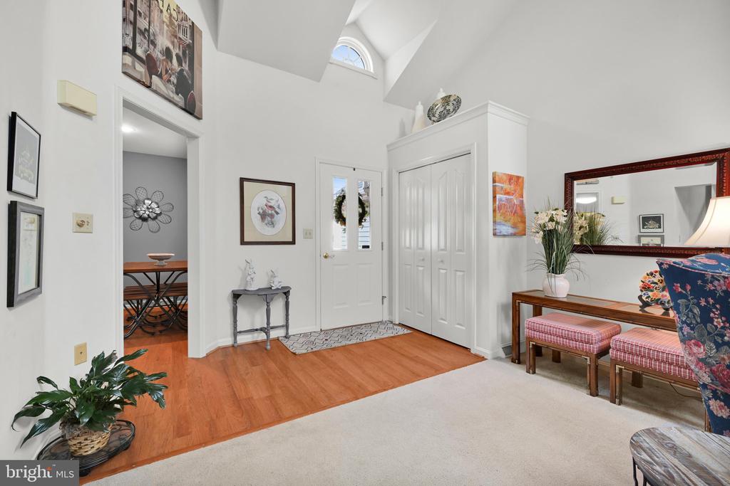 Furnished entry foyer with vaulted ceiling, hardwood floors, white double doors, and a half-moon window.