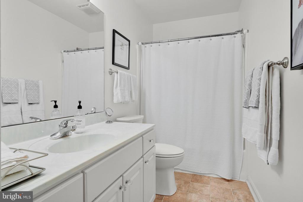 Bathroom with a long white vanity, toilet, and white shower curtain.