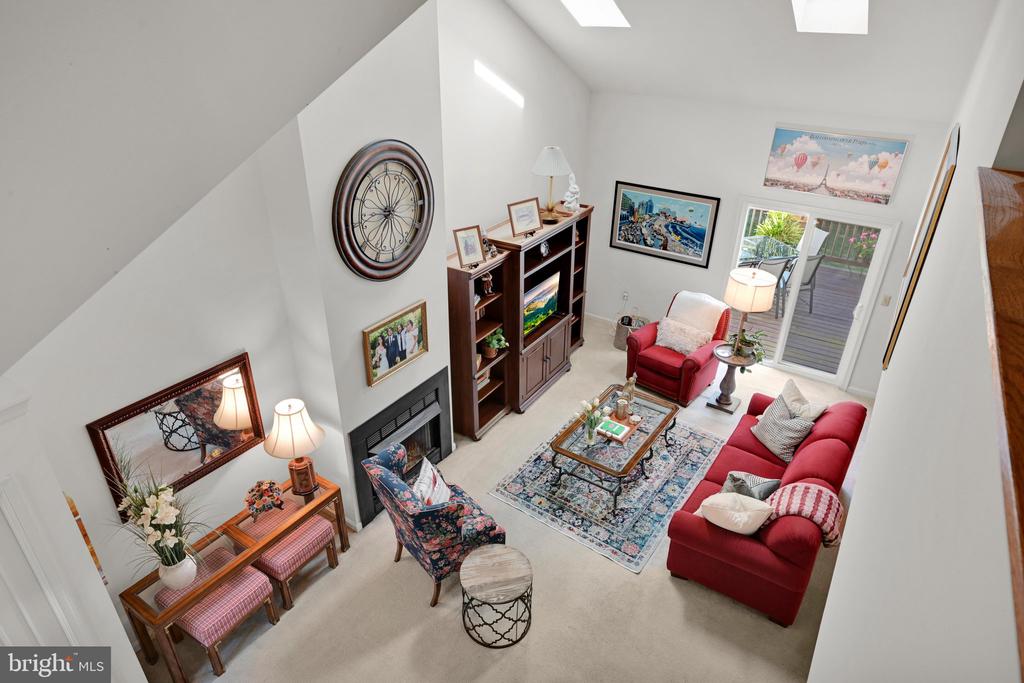 Two-story living room with red sofas, a fireplace, and sliding glass doors to a deck.