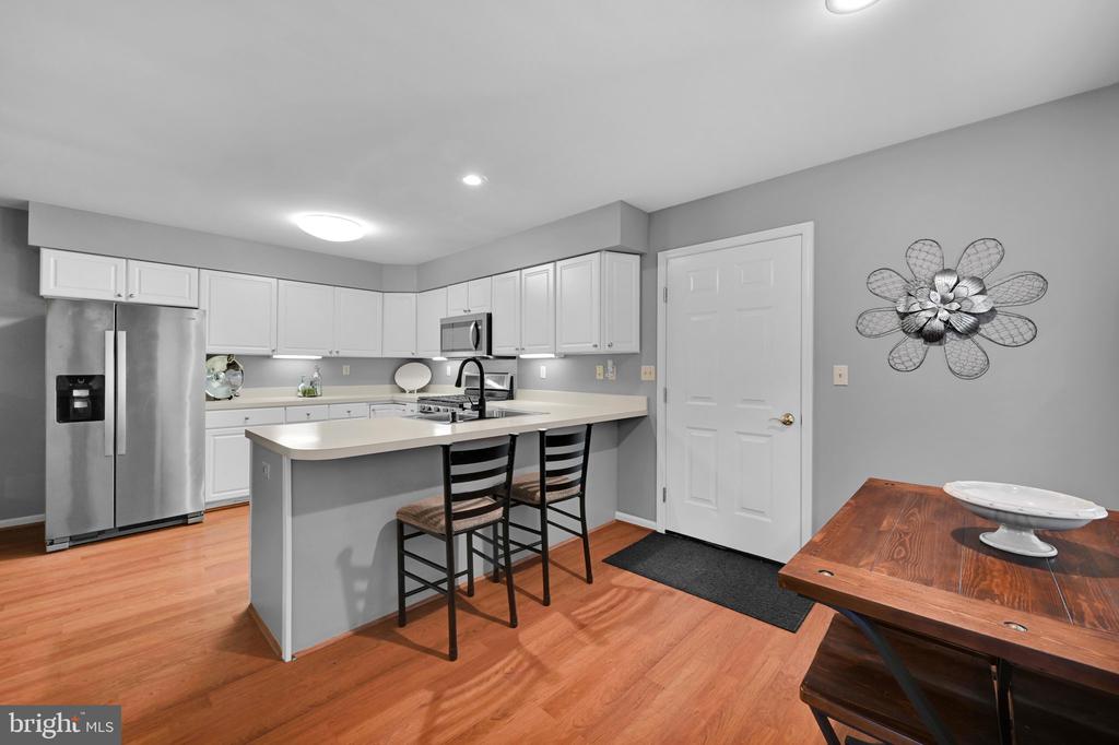 Kitchen with white cabinets, stainless steel appliances, and a peninsula with two stools.