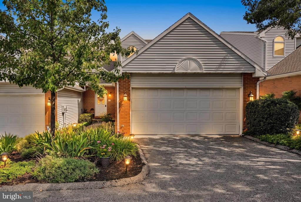 Home exterior with a double garage, brick accents, and landscaped garden beds.