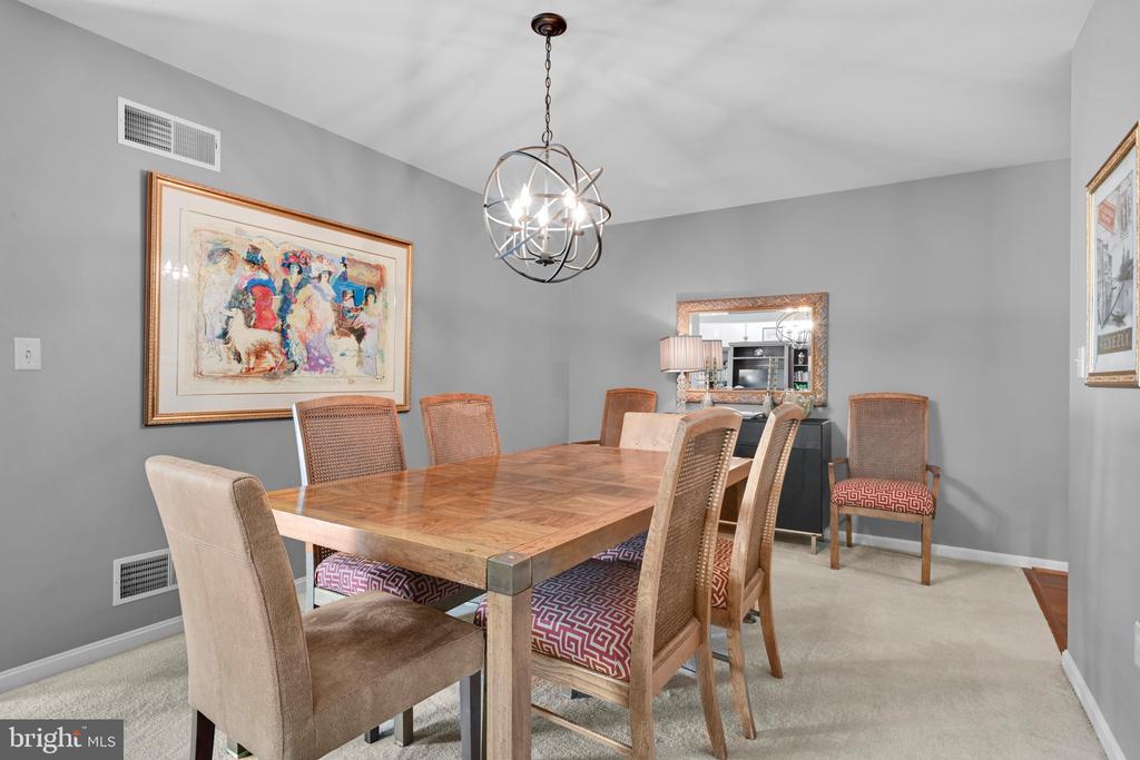 Dining room with a large wooden table, woven-back chairs, and a spherical chandelier.