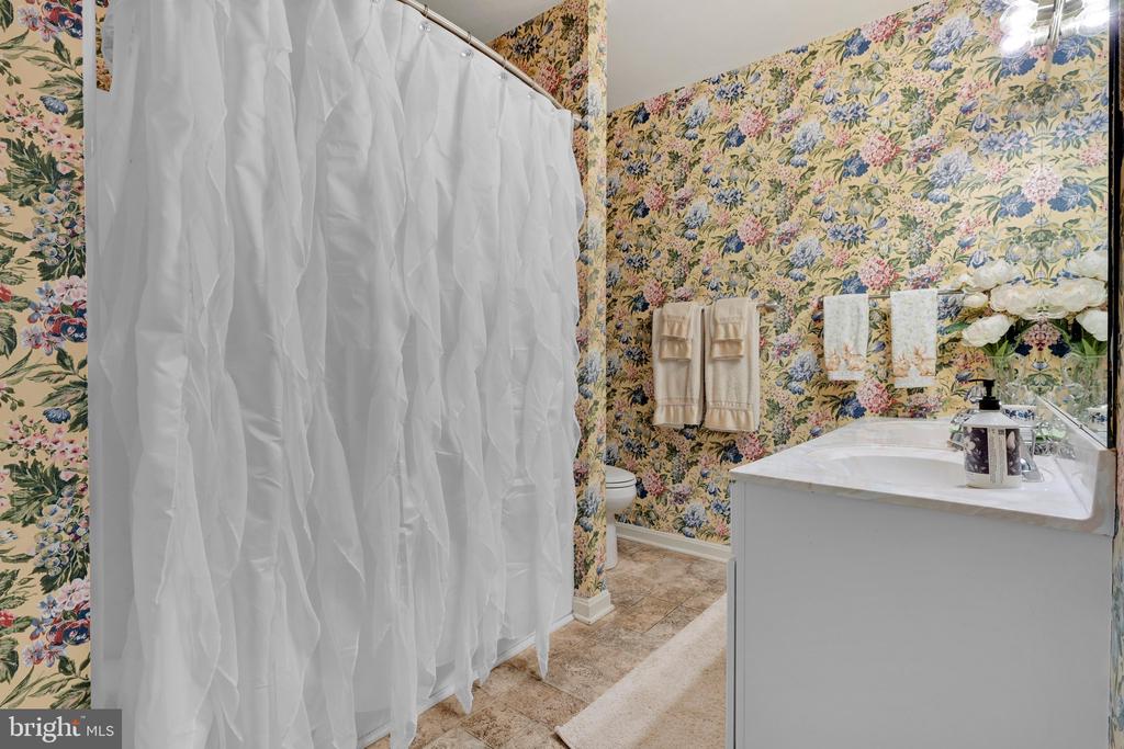 Bathroom with floral wallpaper, a white shower curtain, and a white vanity.